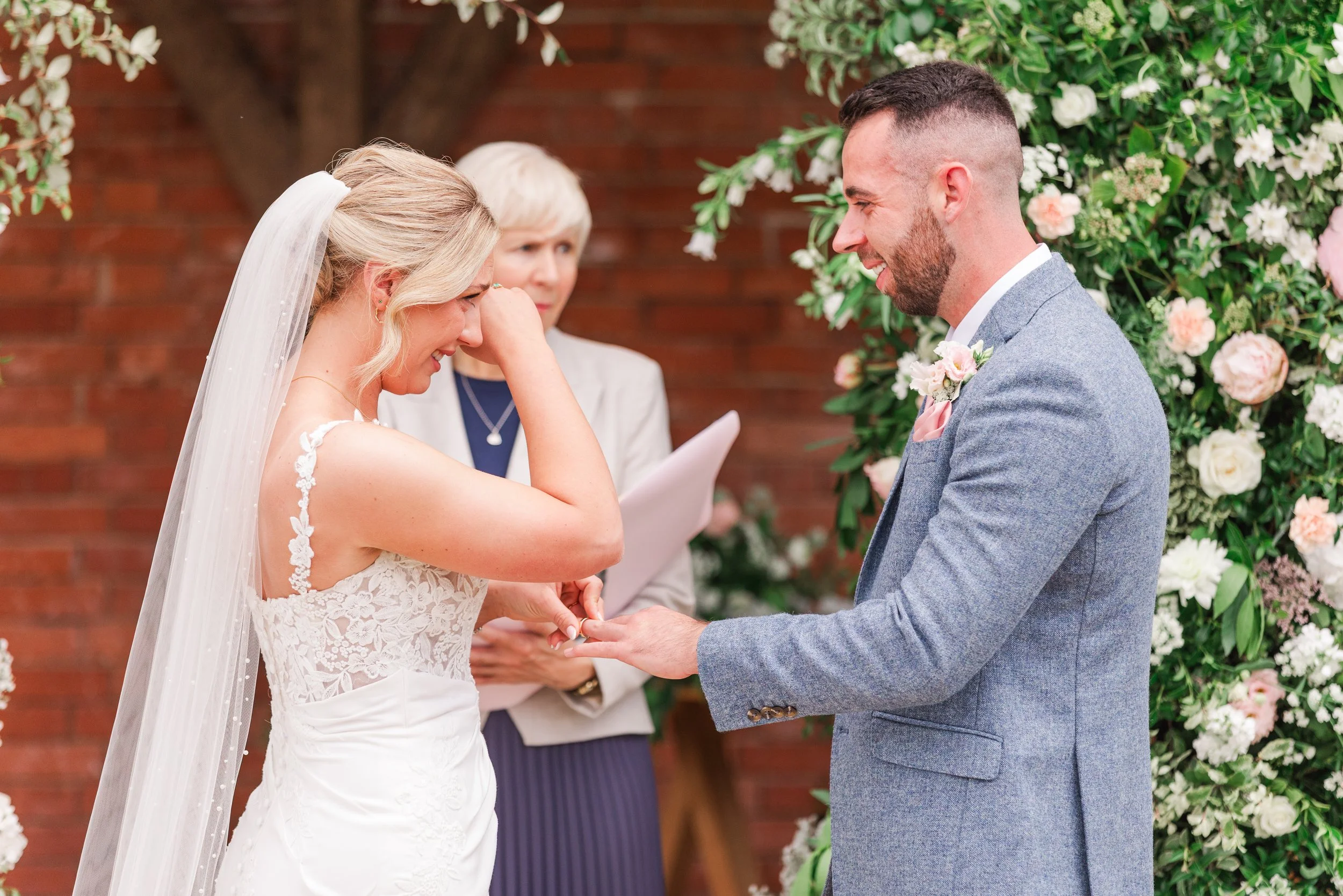 A bride crying during her wedding ceremony in Devon with her groom smiling at her