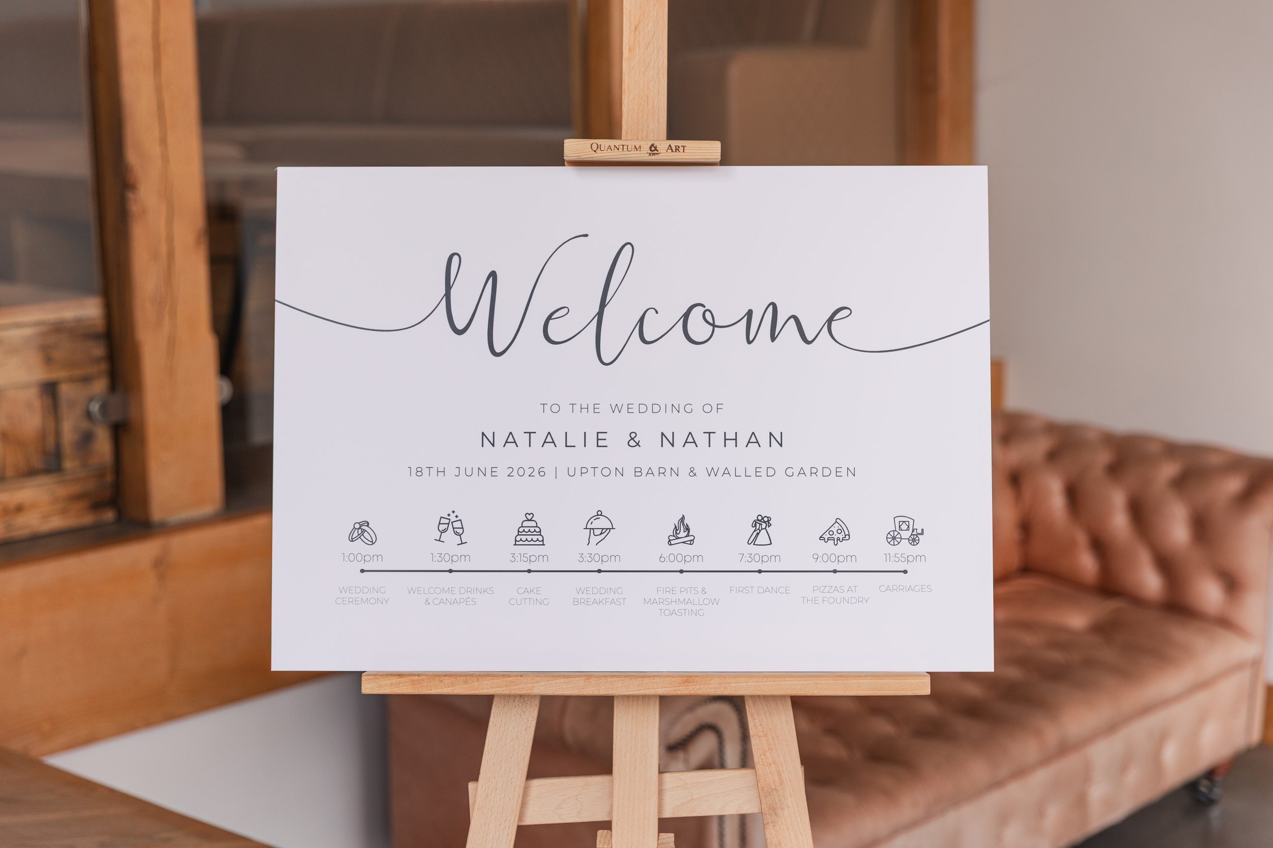 A white wedding welcome sign with black writing on a wooden easel
