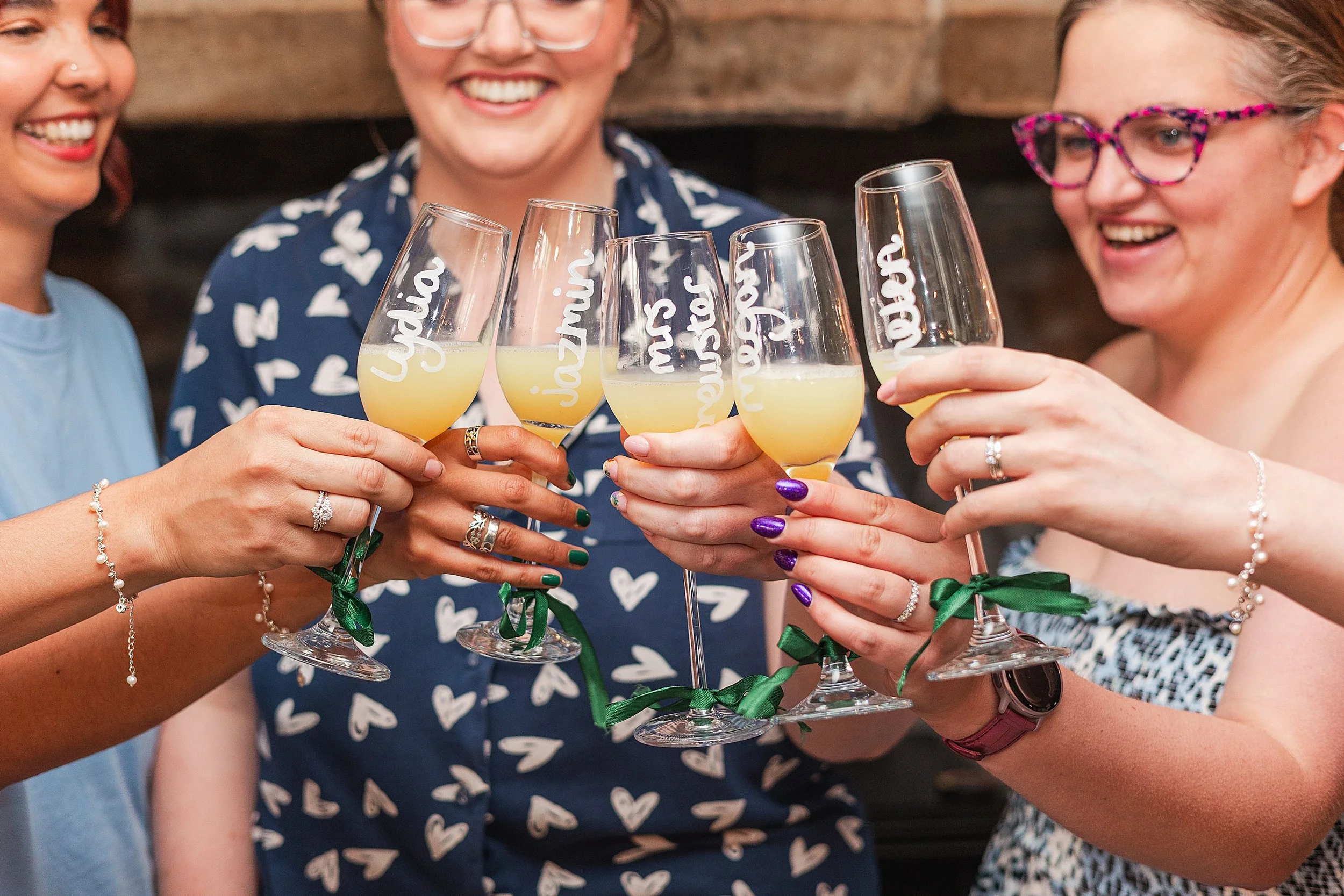 A bride with her bridesmaids clinking their glasses whilst smiling