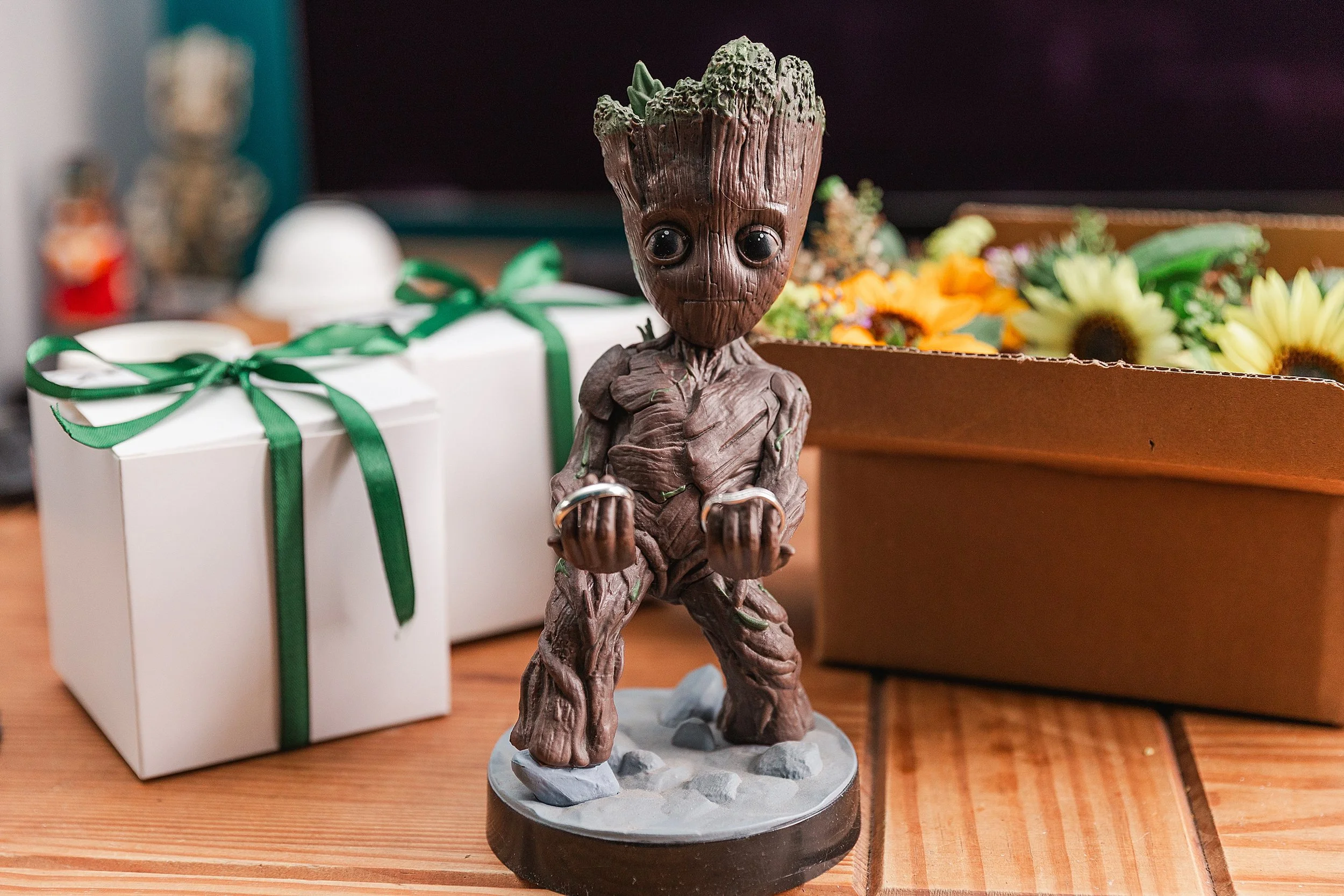 A small statue of Groot holding wedding rings in his hand