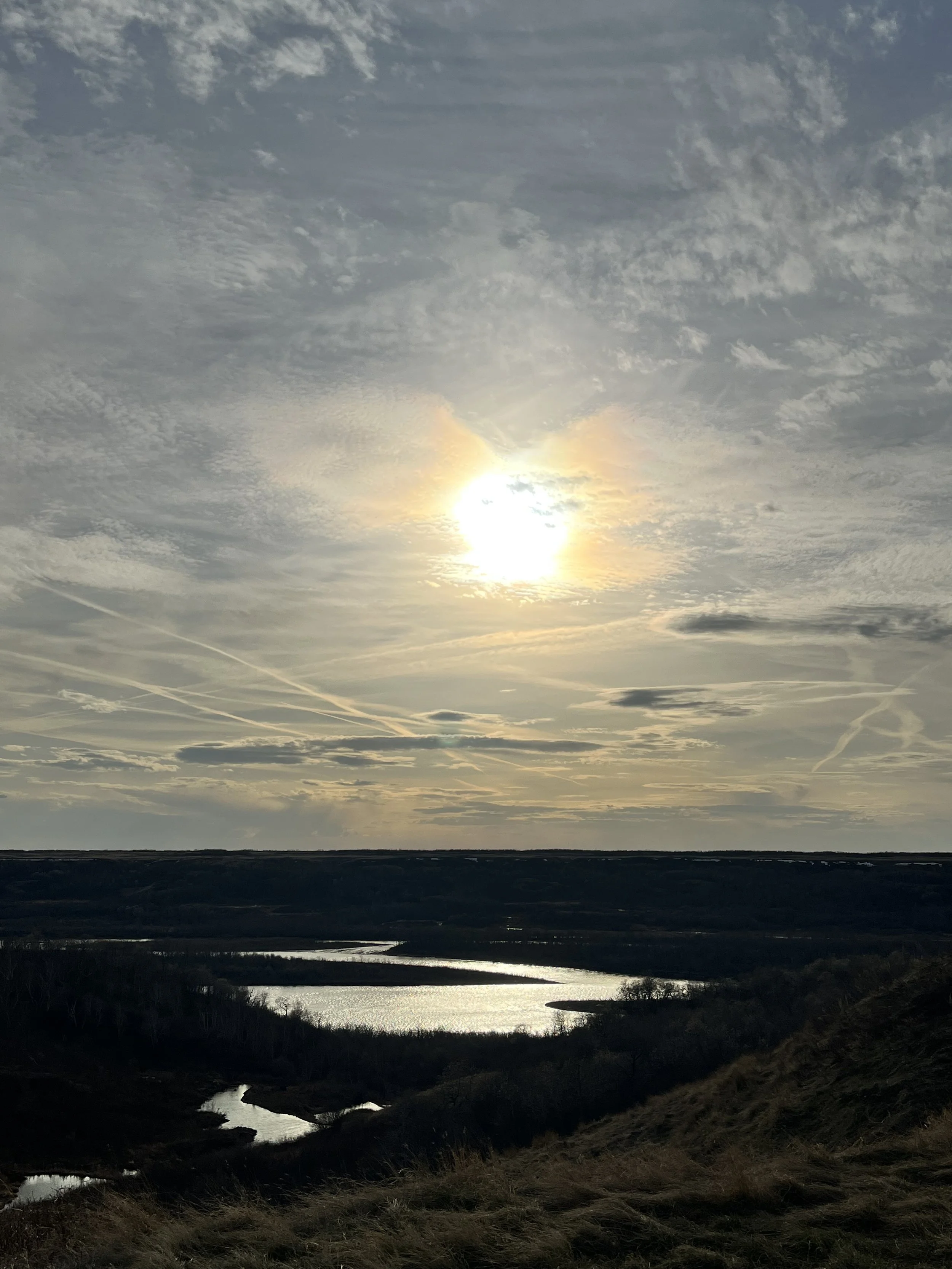 Sun sinking above North Saskatchewan River from highlands at Blue Sky Ranch near Langham, Saskatchewan - Photo by Karla Combres