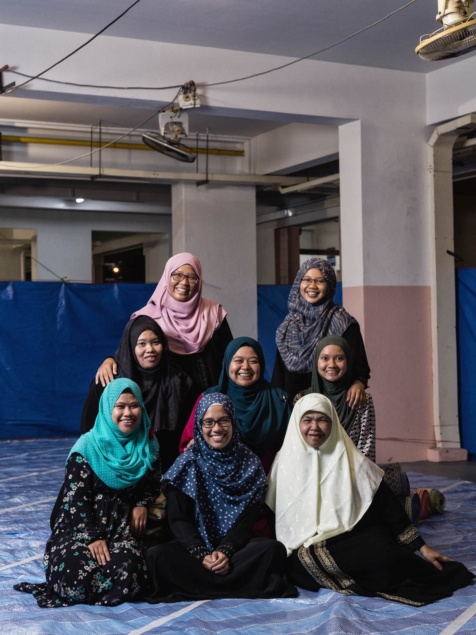 As former students from Boon Lay's Masjid Majapahit – demolished in 2000 – these girls regularly perform their tarawih prayers at Block 978/979 Jurong West St 93. They have attended this musollah for over 10 years. “I have been here since I was 12. Now I’m 28, so it’s been at least 16 years,” one said. Then, they would attend with their parents – now they would attend these prayers with their friends. Though they never knew each other well enough when they were students, they now have a Whatsapp chat group – giving updates on days they would turn up for prayers. And this would be their last year praying together here. They are delighted regardless in getting a new mosque because they have been without one for over 16 years. (Last Row (L-R): Suhada, Nasuha, Middle Row (L-R): Suziane, Nur Zaida, Nurhidaya, Front Row (L-R): Faezah, Nurul, Cik Kalsom)