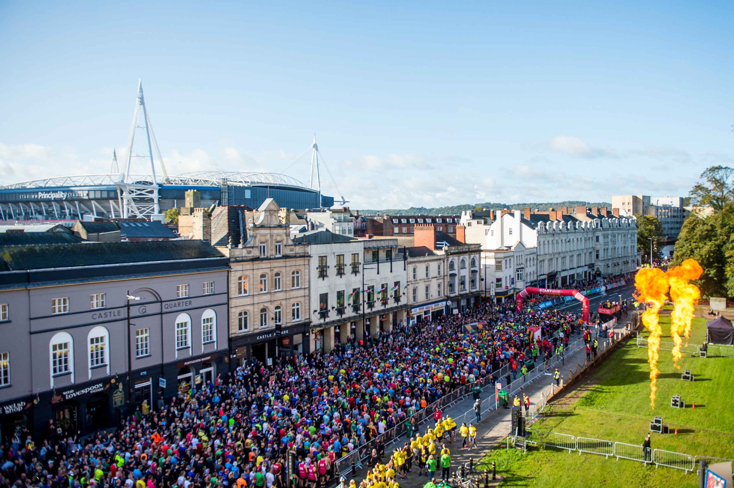 An enormous crowd of runners at the start of the Cardiff Half Marathon, with the Principality Stadium in the background.