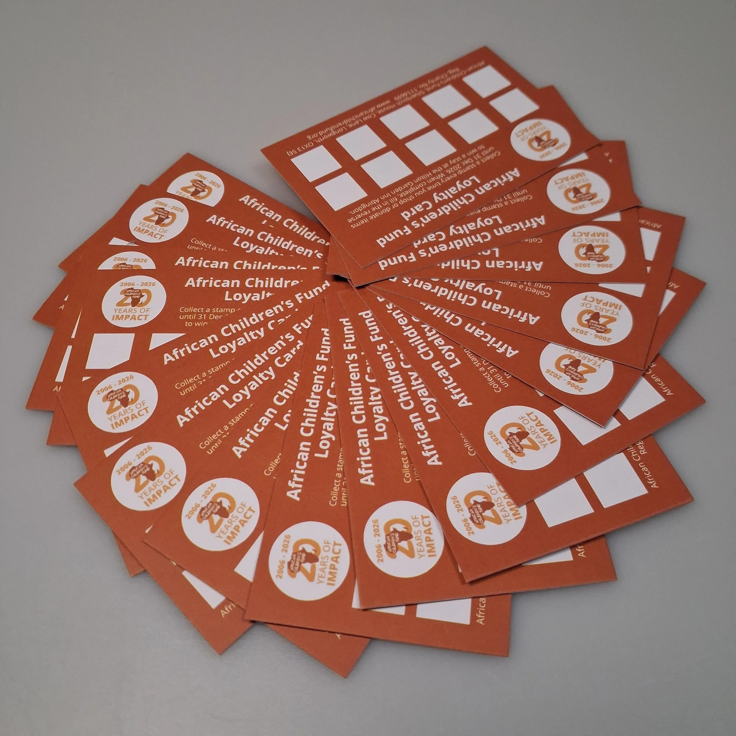 A batch of African Children's Fund 20th Anniversary Loyalty Cards, arranged in a circle.