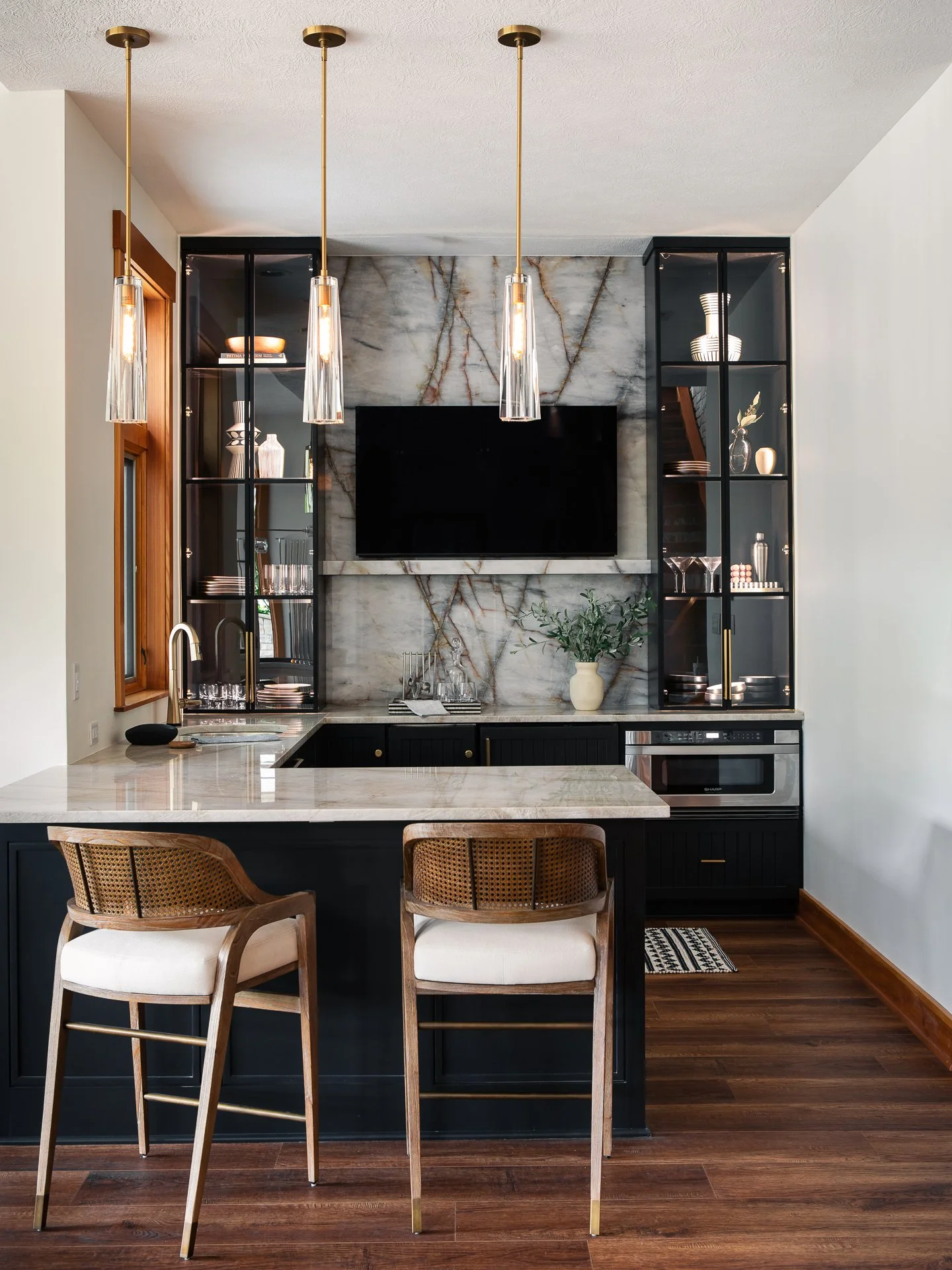 A basement bar with a lot of pizzazz! At Grandview, some of the cabinetry was salvageable, but the angled peninsula and upper cabinets needed to go. We gave the existing cabinets a fresh coat of paint, added statement making glass front cabinets, and