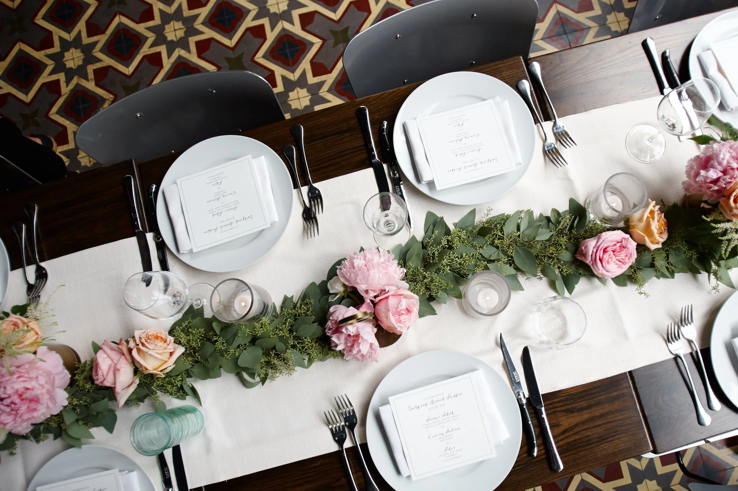 Bird's-eye view of a table set for a private event with custom menus and floral arrangements down the center.jpg