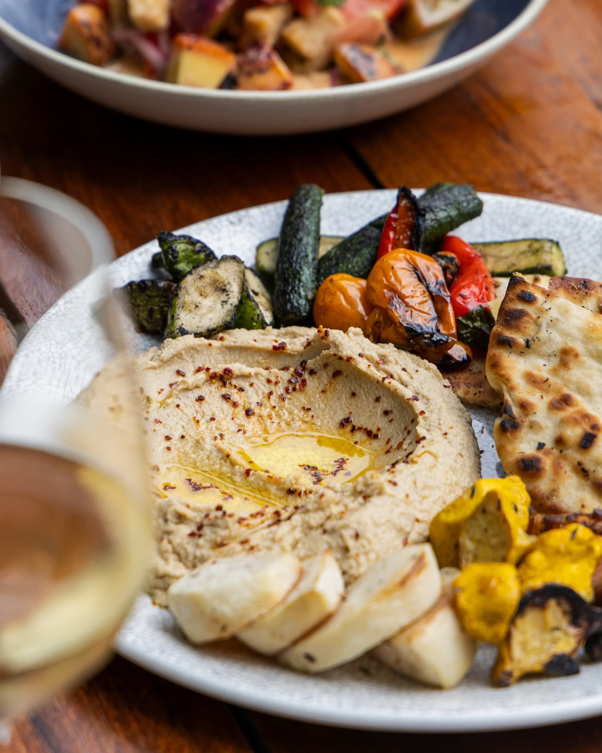 Summer on a plate, best enjoyed on the patio. Hummus &amp; Woodfired Summer Veggies with local farmers market vegetables, grilled lemon, za&rsquo;atar and grilled naan.
