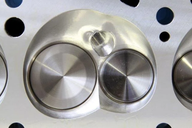 Edelbrock’s new Performer RPM CNC for Pontiac V8 features a fully machined combustion chamber with a pronounced heart shape. It’s easy to see how this chamber differs from the scalloped-shaped chamber of the Performer RPM. Notice that the spark plug…