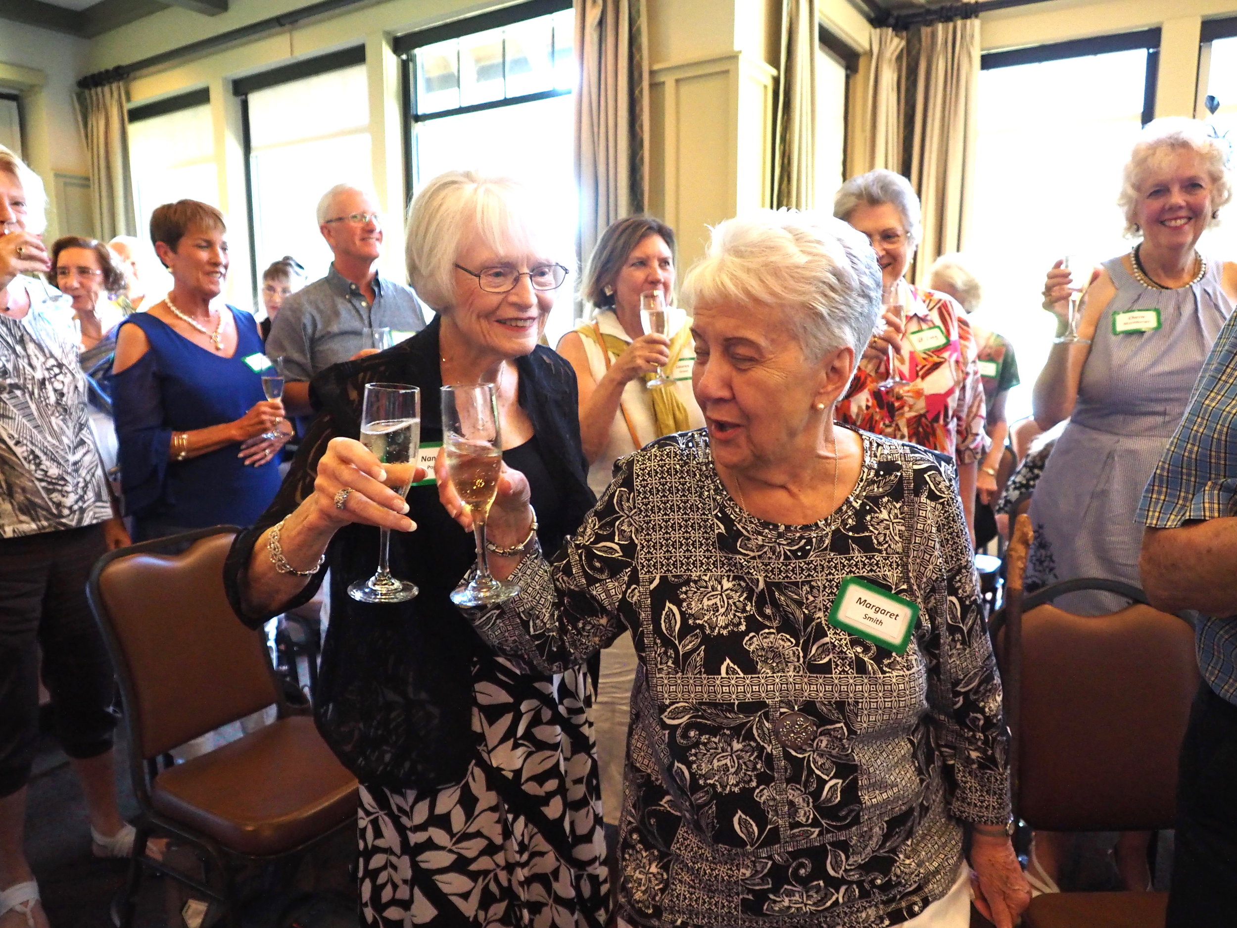 Nancy Popp and Margaret Smith are joined by other members in a toast.	