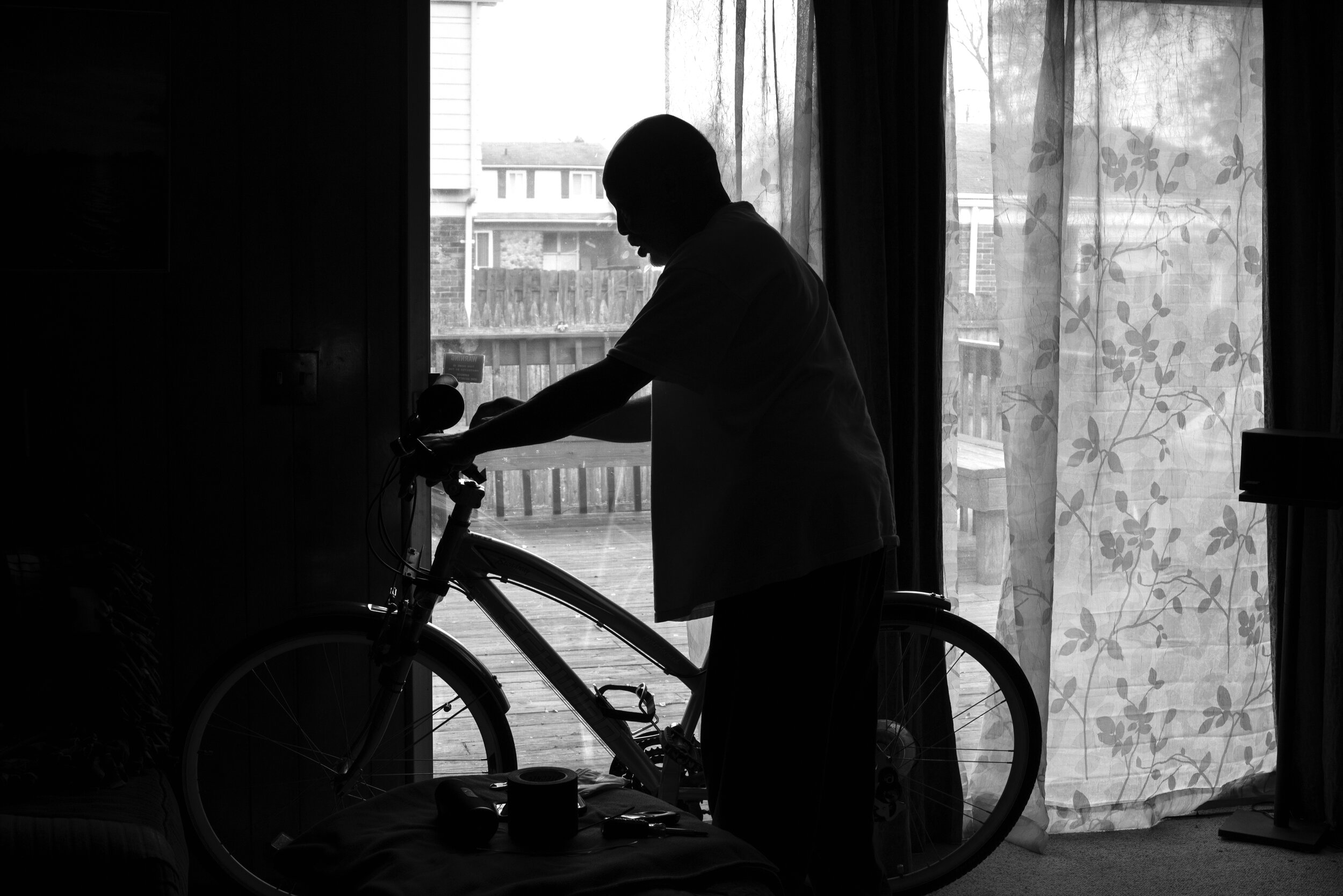   My dad has several bicycles that he has found, repaired and has made his own personal customizations to. He also gives bikes away to people who are in need of one. Here, he makes alterations to one of his bicycles in our family room at our home in 