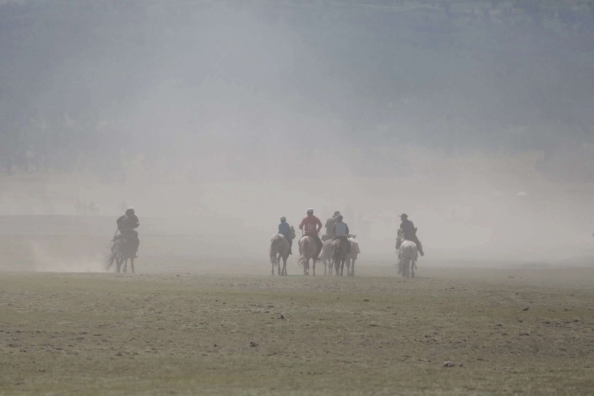 The riders, raising much dust, ride to the starting point of the races