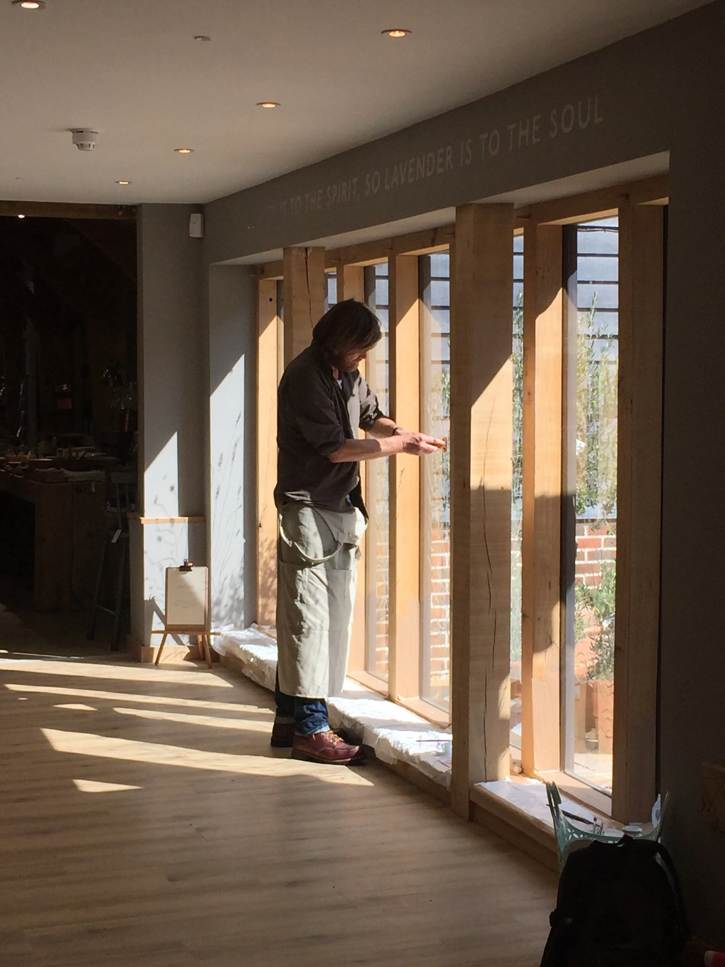 Illustrator Dan Williams paints his signature lavender stems and bee's onto the windows at Long Barn. (Copy)