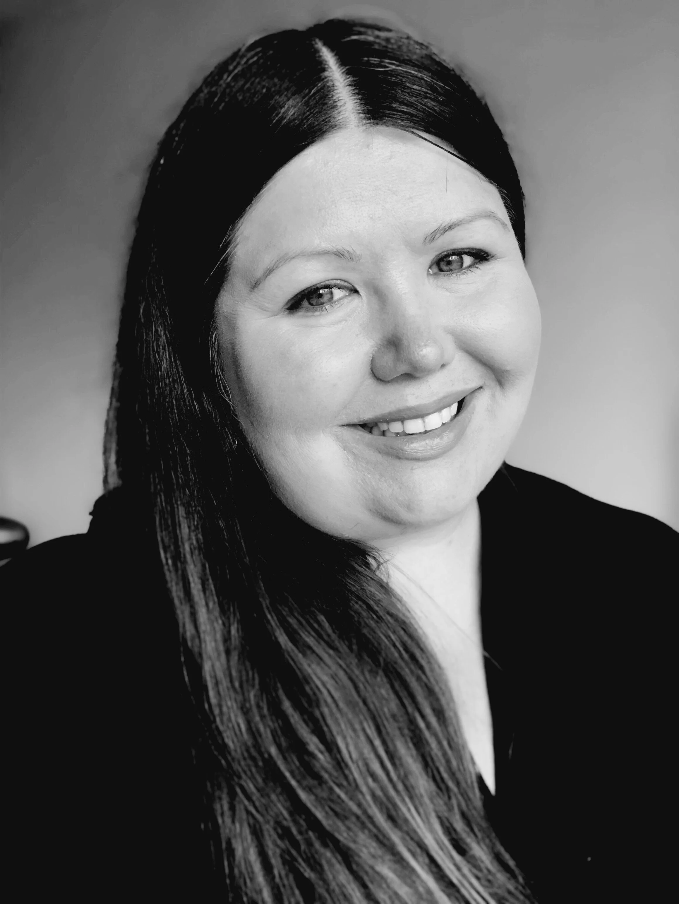 Black and white portrait of a woman with long dark hair, smiling at the camera.