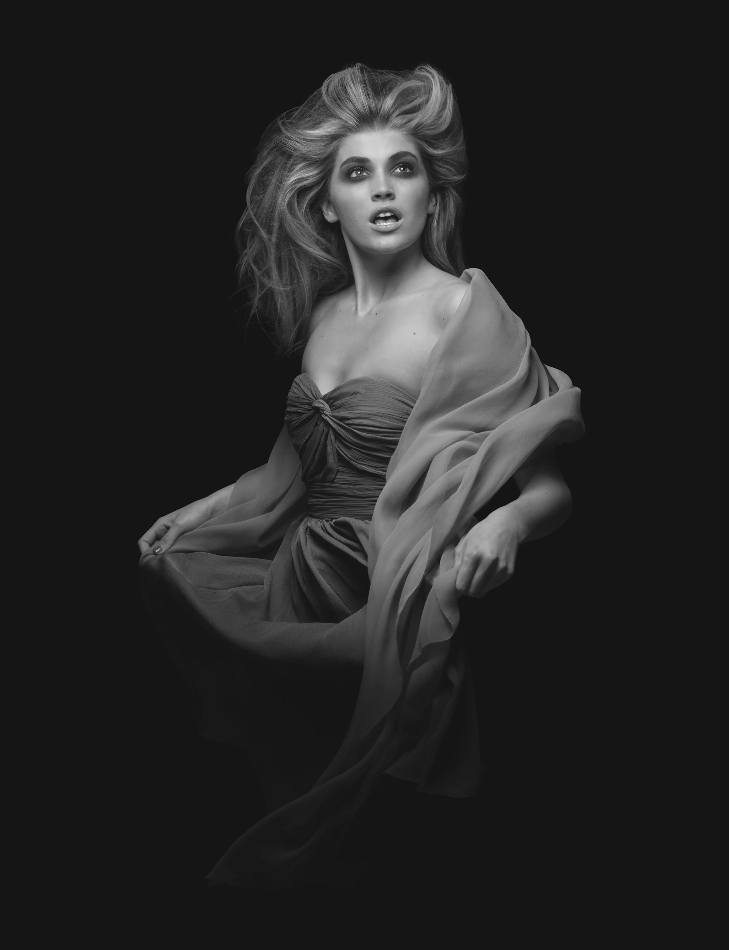 Female model with cosmetic makeup, wind blown hair, gown and shawl black and white studio fashion portrait retouching