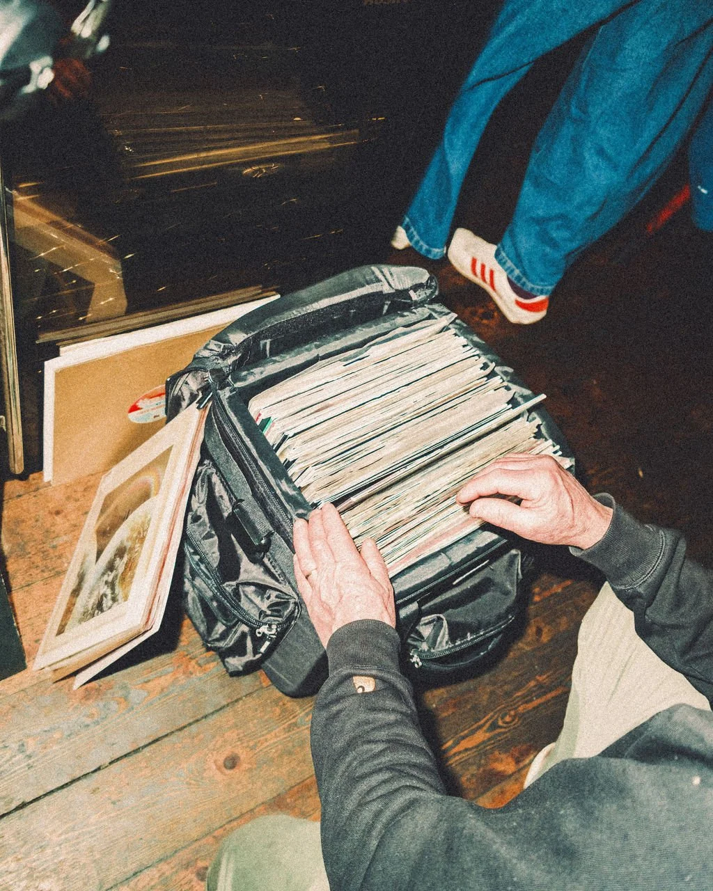 Person looking through a bag of vinyl records at a record store.