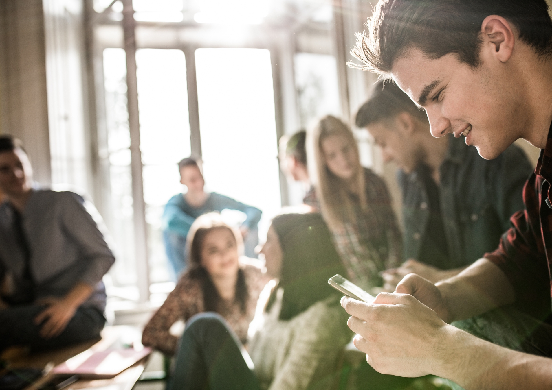 Smiling-teenage-student-online-messaging-on-cell-phone-during-a-break-in-the-classroom.-902808818_2125x1416.jpeg