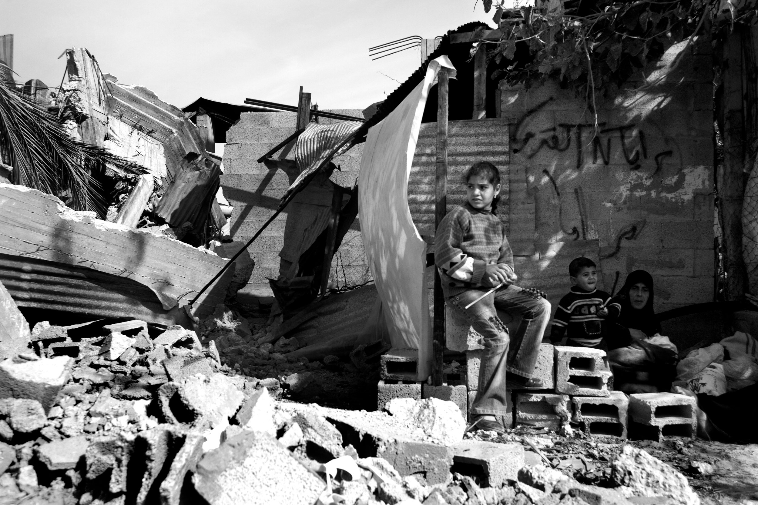 A family in the rubble of their home which was destroyed during Operation Cast Lead, Gaza 2009.