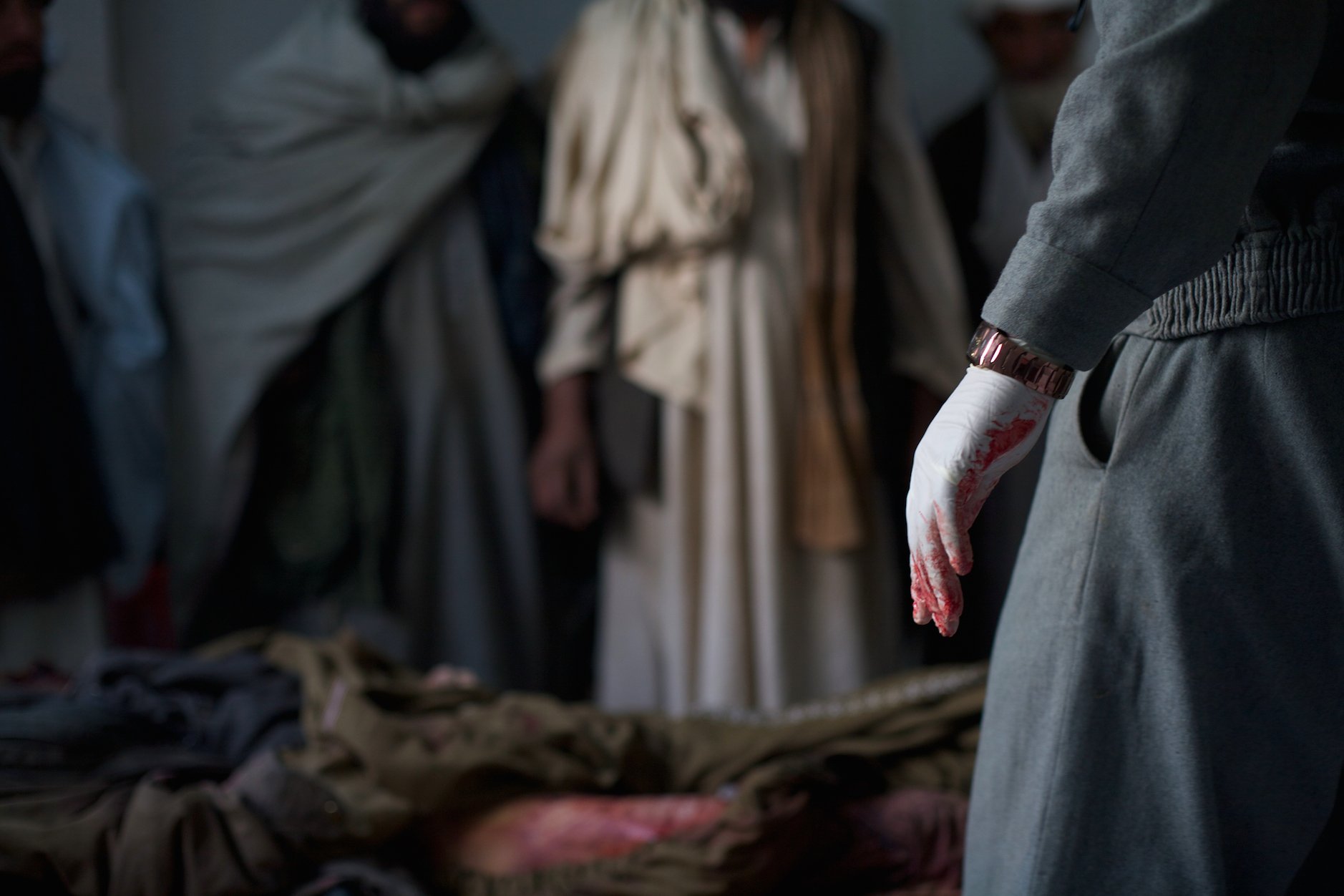  Afghan police investigate the body of a man they suspected was killed by coalition forces in Helmand, Afghanistan, 2010. An estimated 2,800 Afghan civilians were killed in the year.  