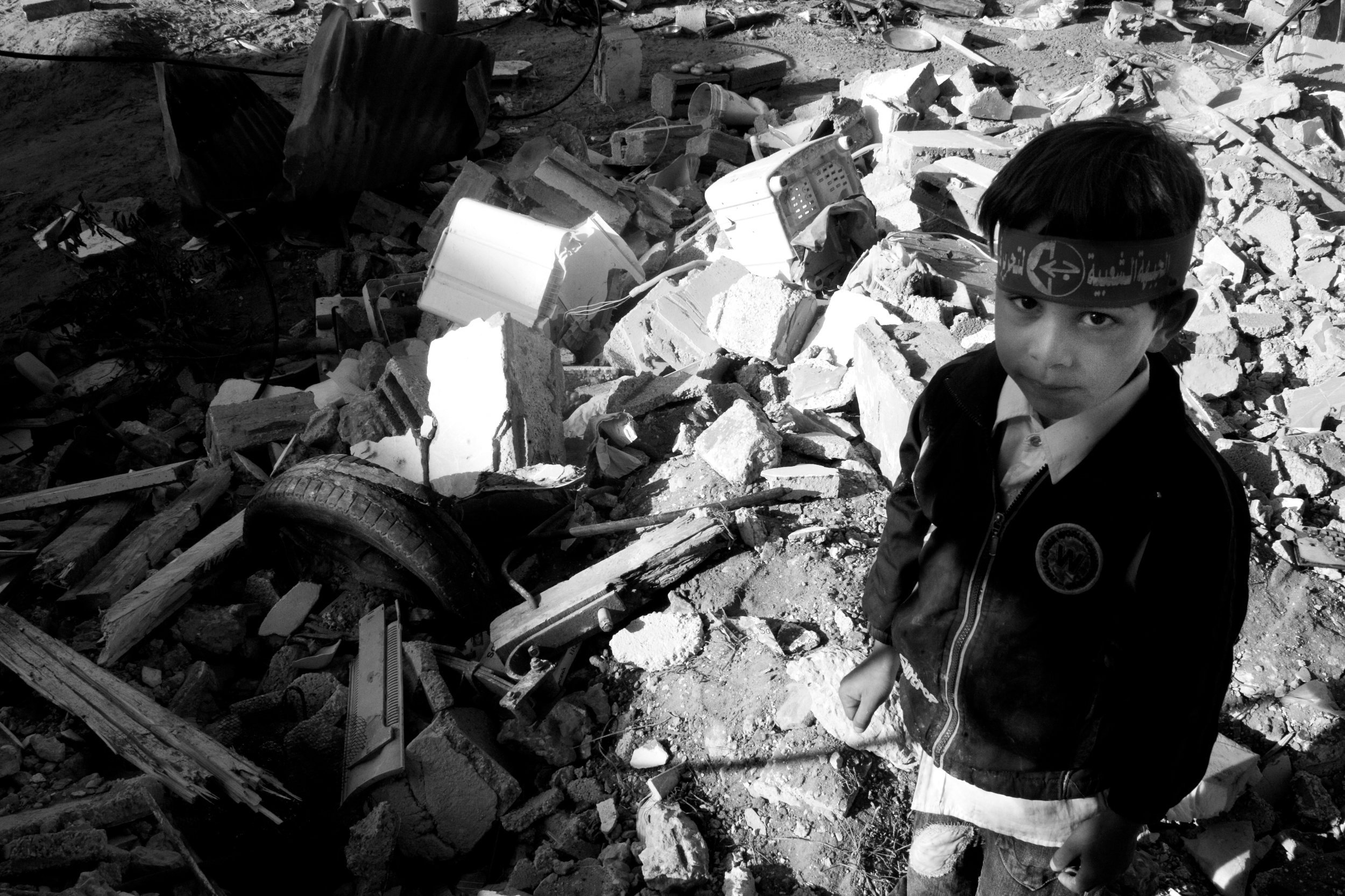 A child stands in the remains of his home in Khan Younis, Gaza 2009. An estimated 40,000 buildings were demolished during the 22 day war between Israel and Hamas.