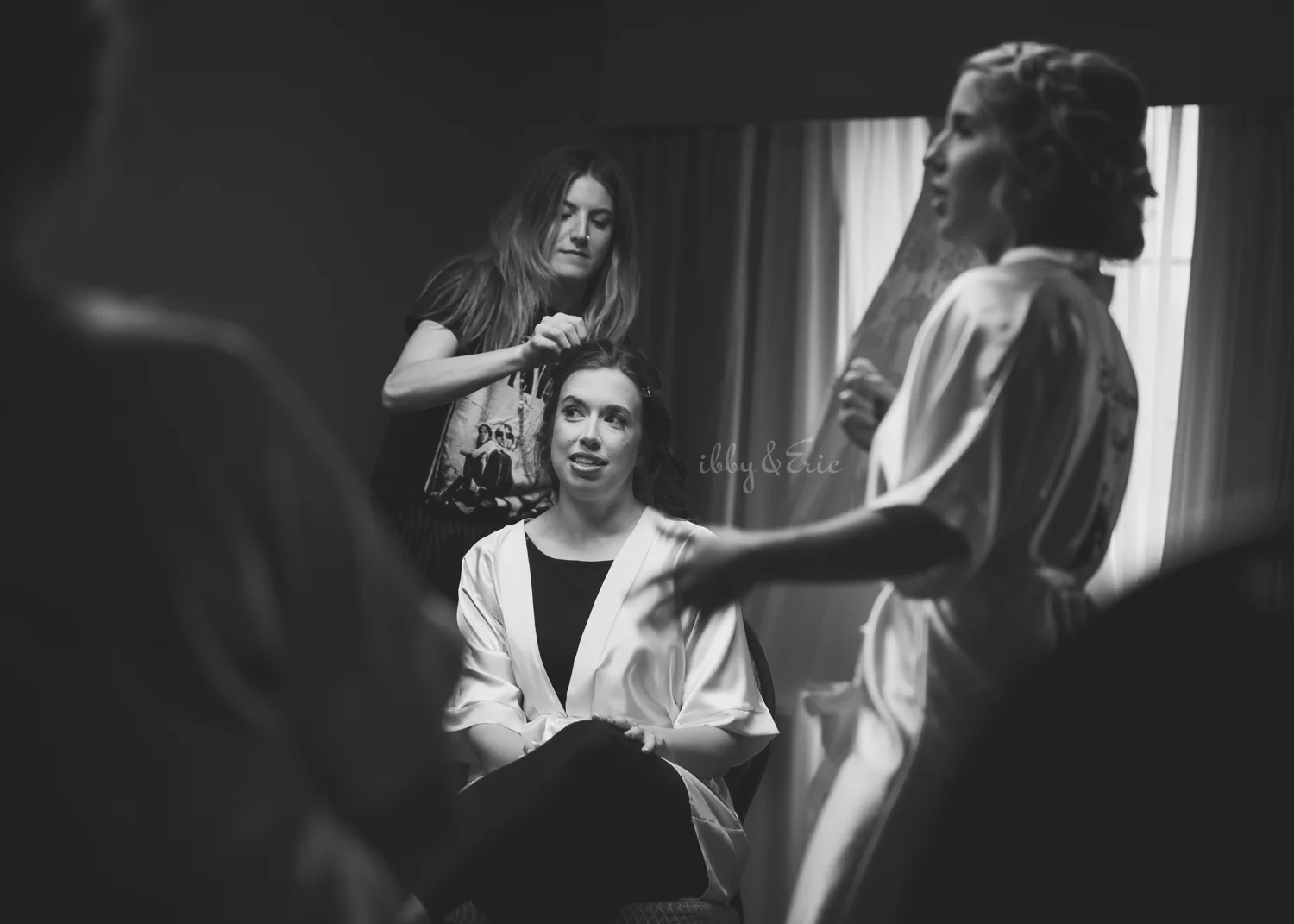 Black and white photo of a hair stylist from Carve Beauty Bar putting the finishing touches on the brides hairstyle.