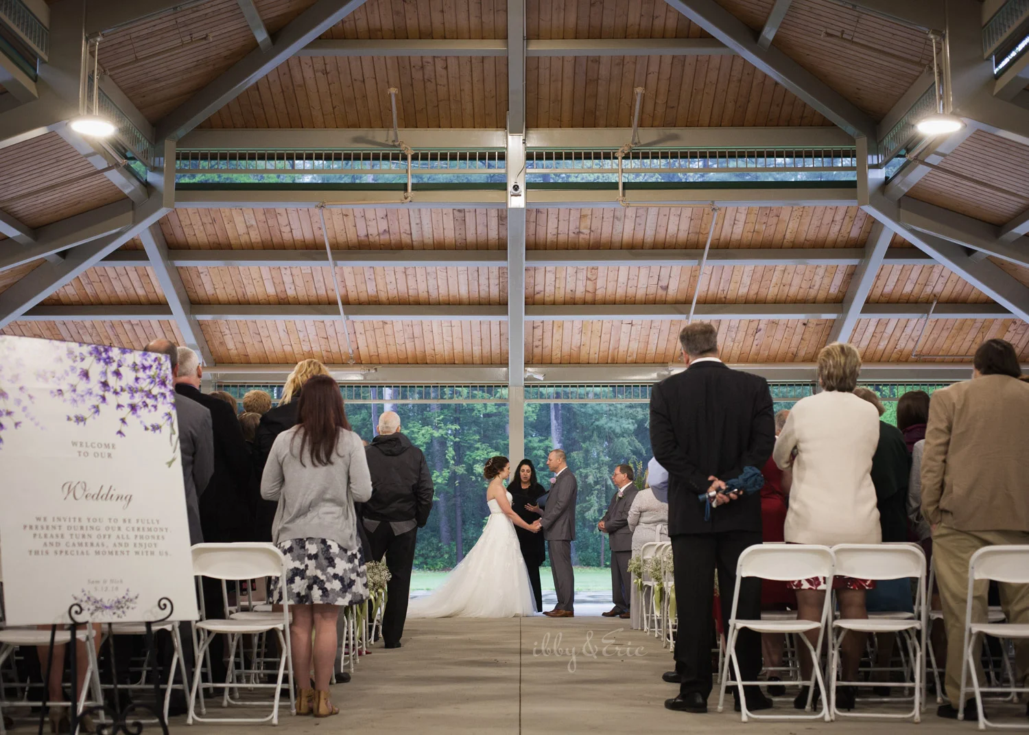 Wide angle photo of a bride and groom's wedding ceremony at the Beveridge Pavillion at Stanley Park.