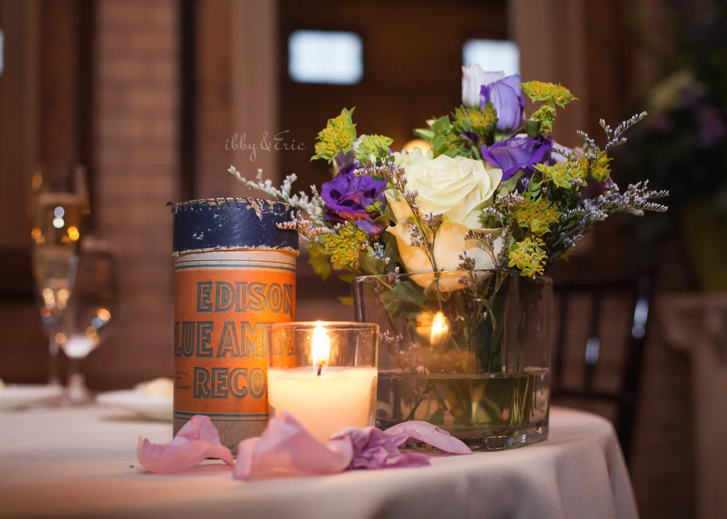 Wedding table centerpiece with edison records, candles, and purple flowers.