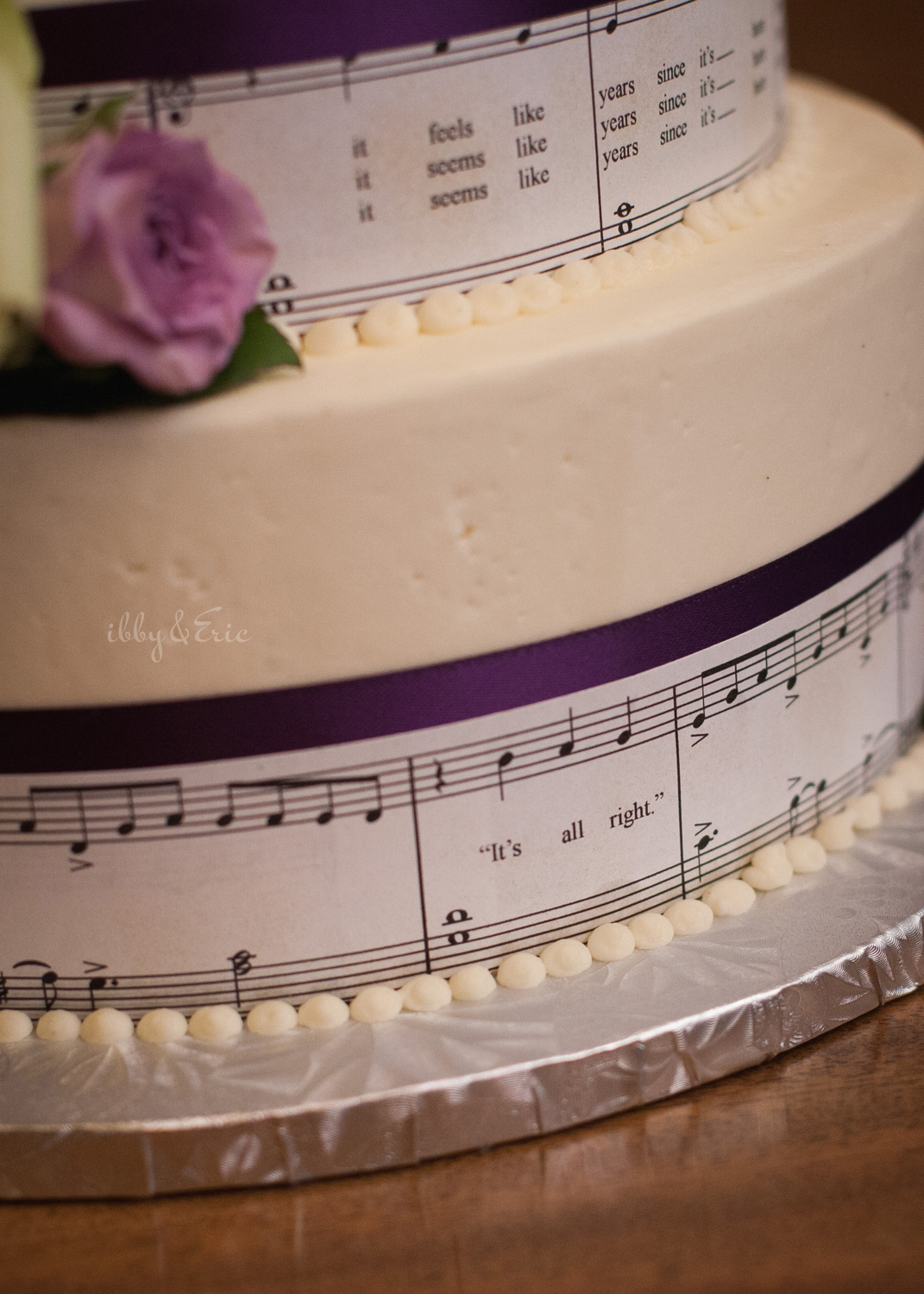 Close up of the side of a tiered wedding cake with a James Taylor sheet music band wrapped around each layer