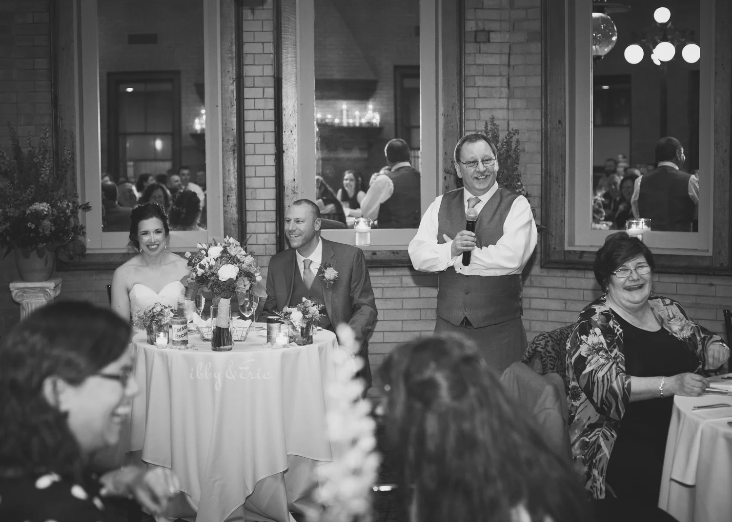 The bride and groom laugh as the best man gives a speech at the Union Station Northampton wedding reception