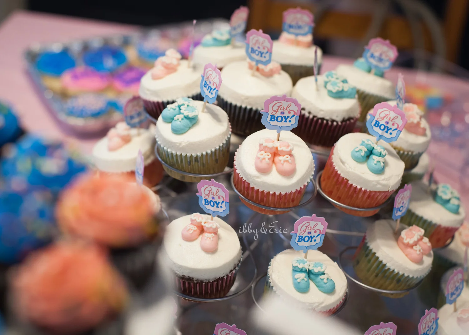 Cupcake display with pink and blue baby shoe decorations.