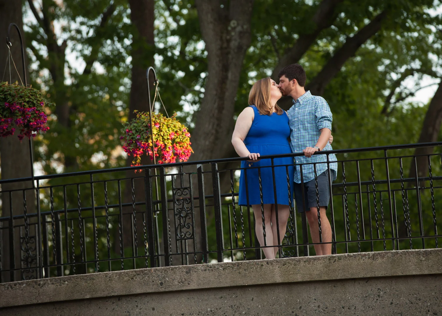 A couple wearing blue kisses on a bridge during their city engagement photos in Worcester, Massachusetts.