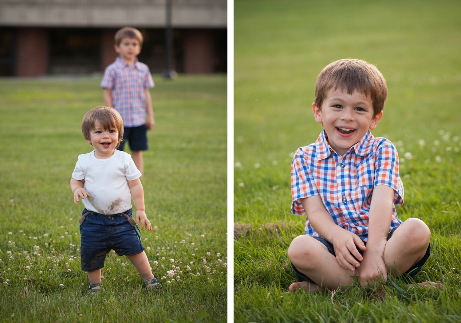 Toddler boy wearing muddy white shirt smiles with his brother in the background, and a boy wearing a blue and orange plaid shirt sits in the grass and laughs.