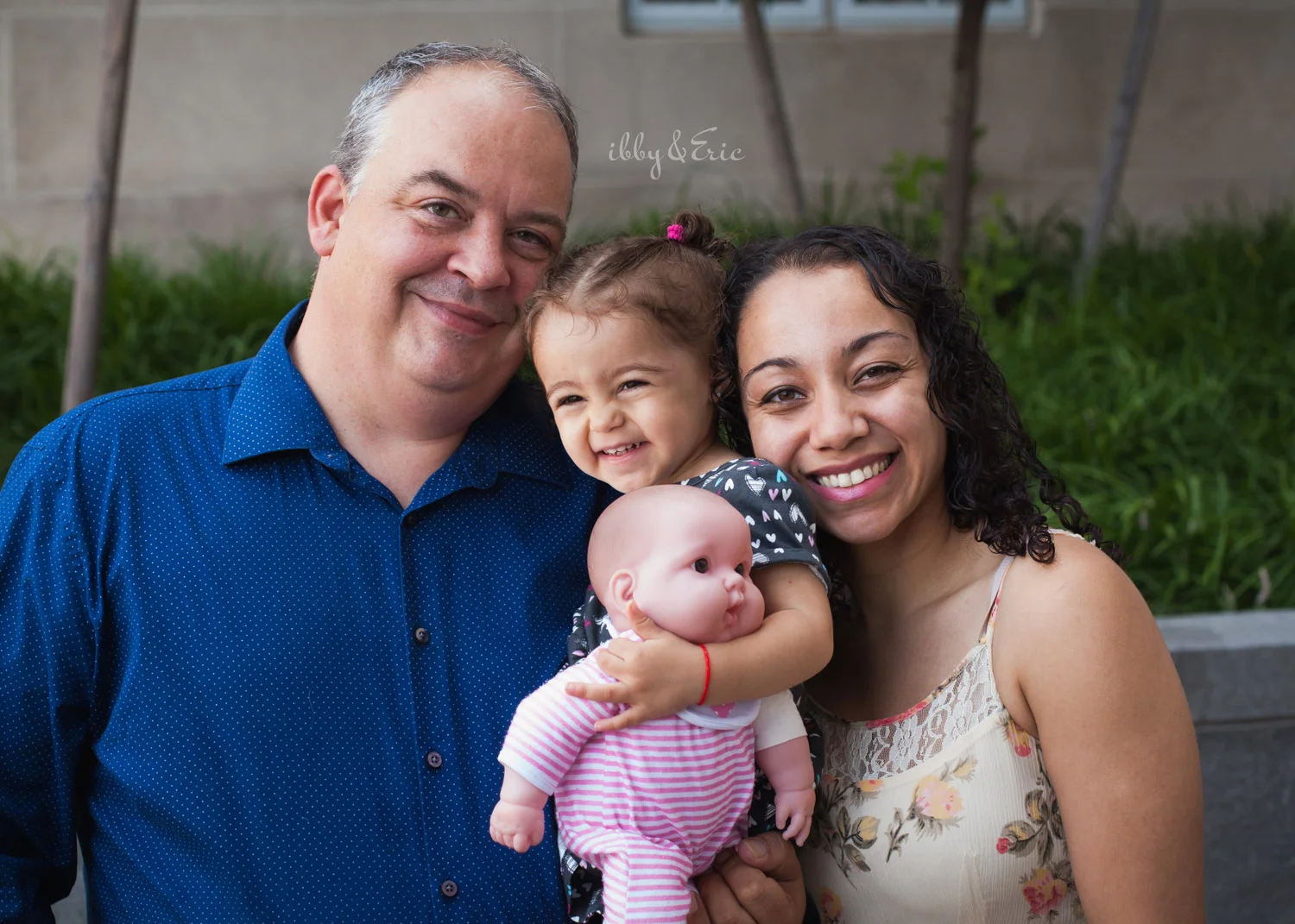 Mom, dad, and two year old daughter holding a baby doll smile together after their adoption ceremony in Greenfield, MA.