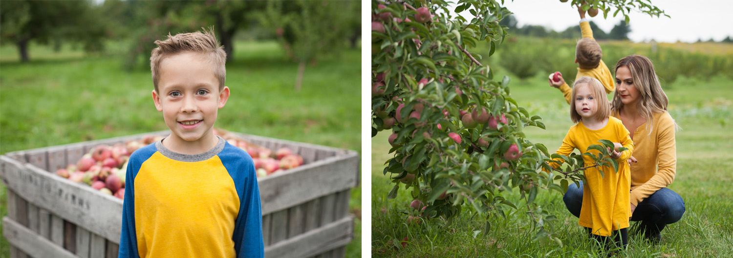 7 year old boy wearing yellow and blue smiles in front of a giant wooden crate of apples & a young girl in dress picks apples with her mom.
