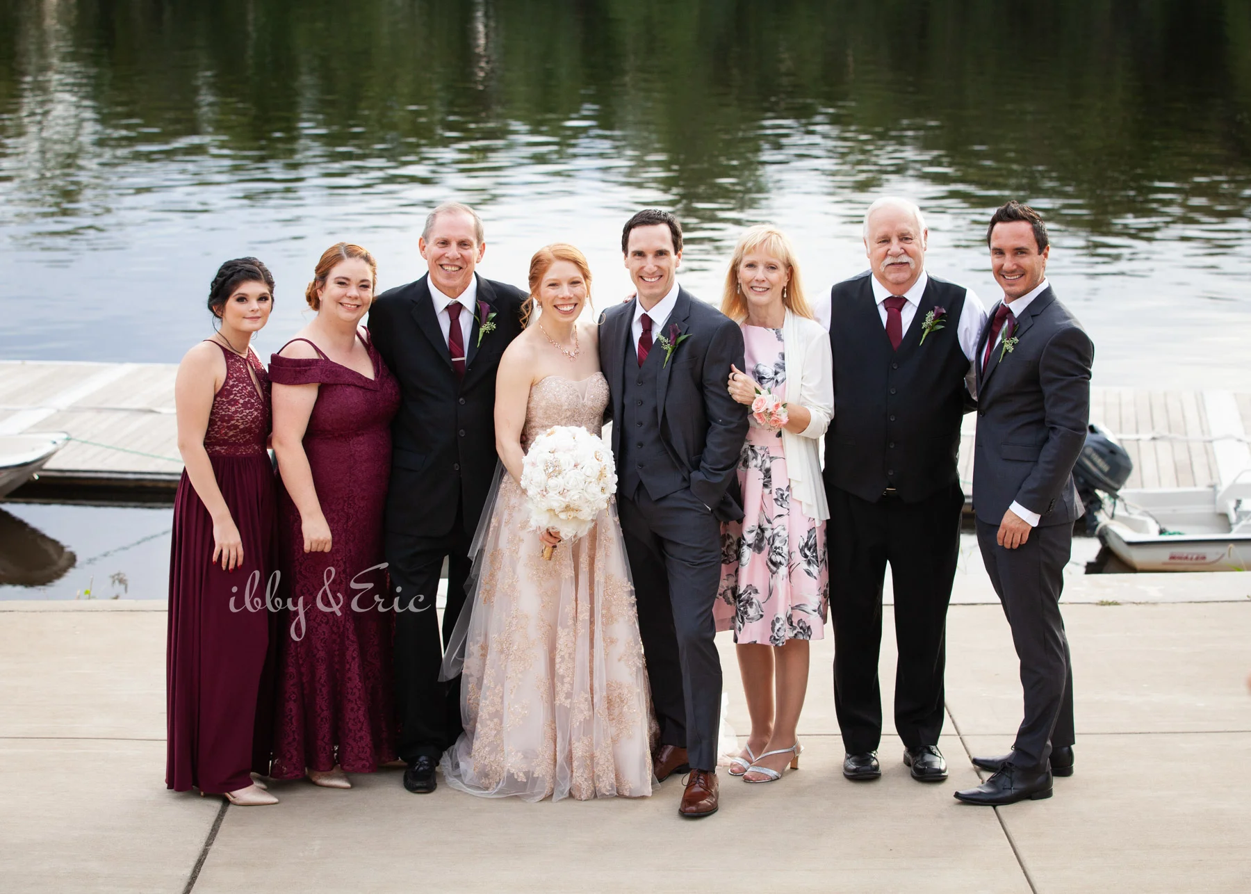 The bride and groom’s families stand together by the dock at the Glastonbury Boathouse for a riverfront family photo.