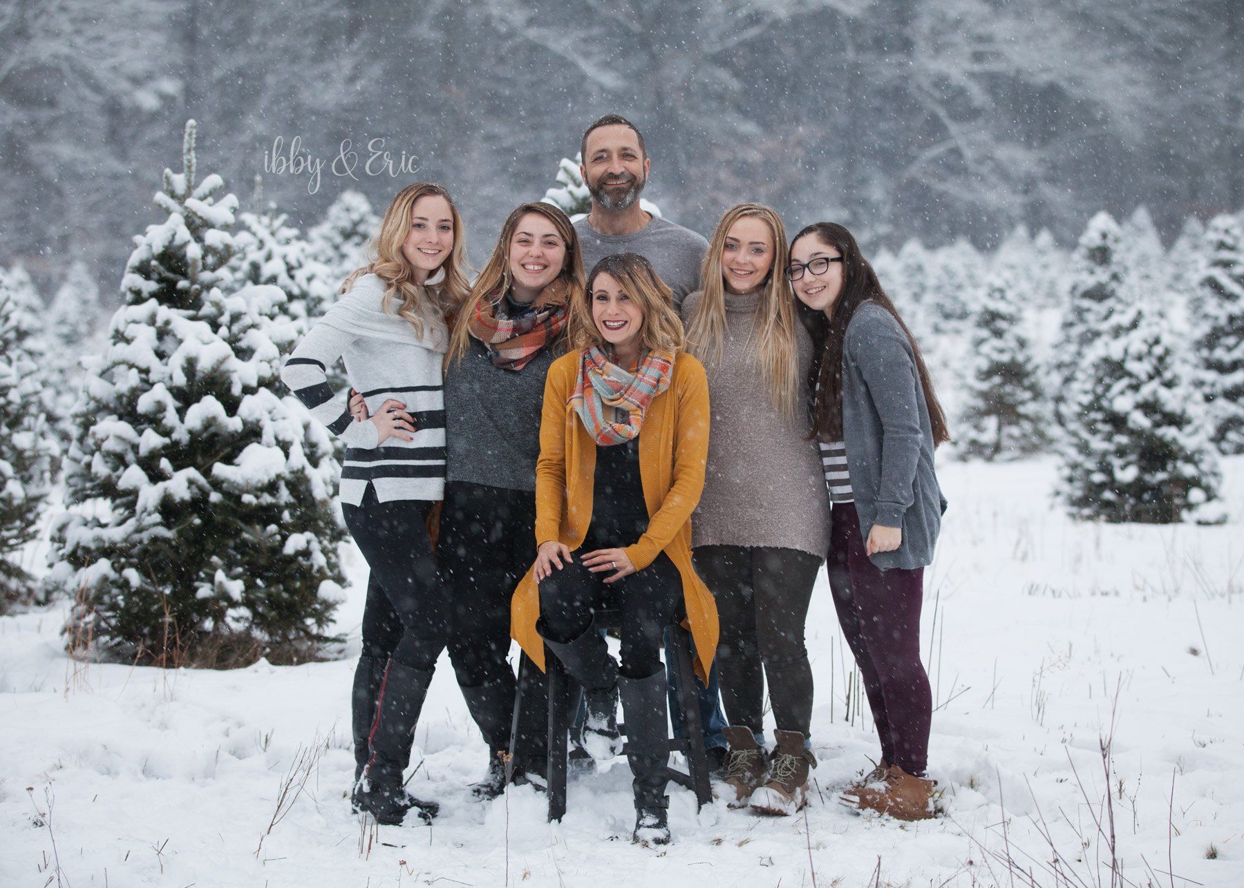 4 girls hug their dad & surround their step mom wearing mustard yellow during a snowstorm in western Massachusetts.