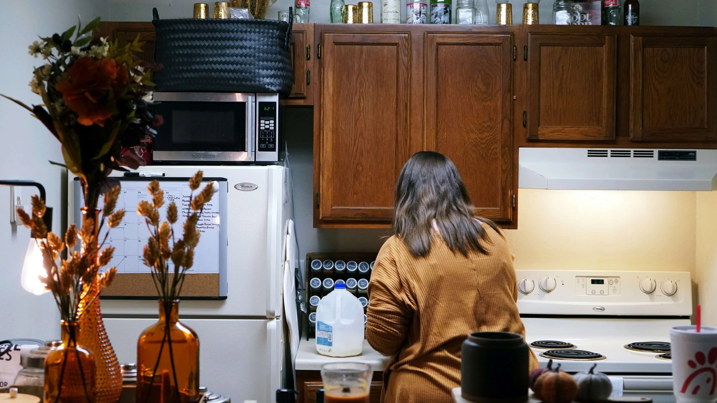 Woman standing in a home kitchen preparing food in a calm, everyday setting.