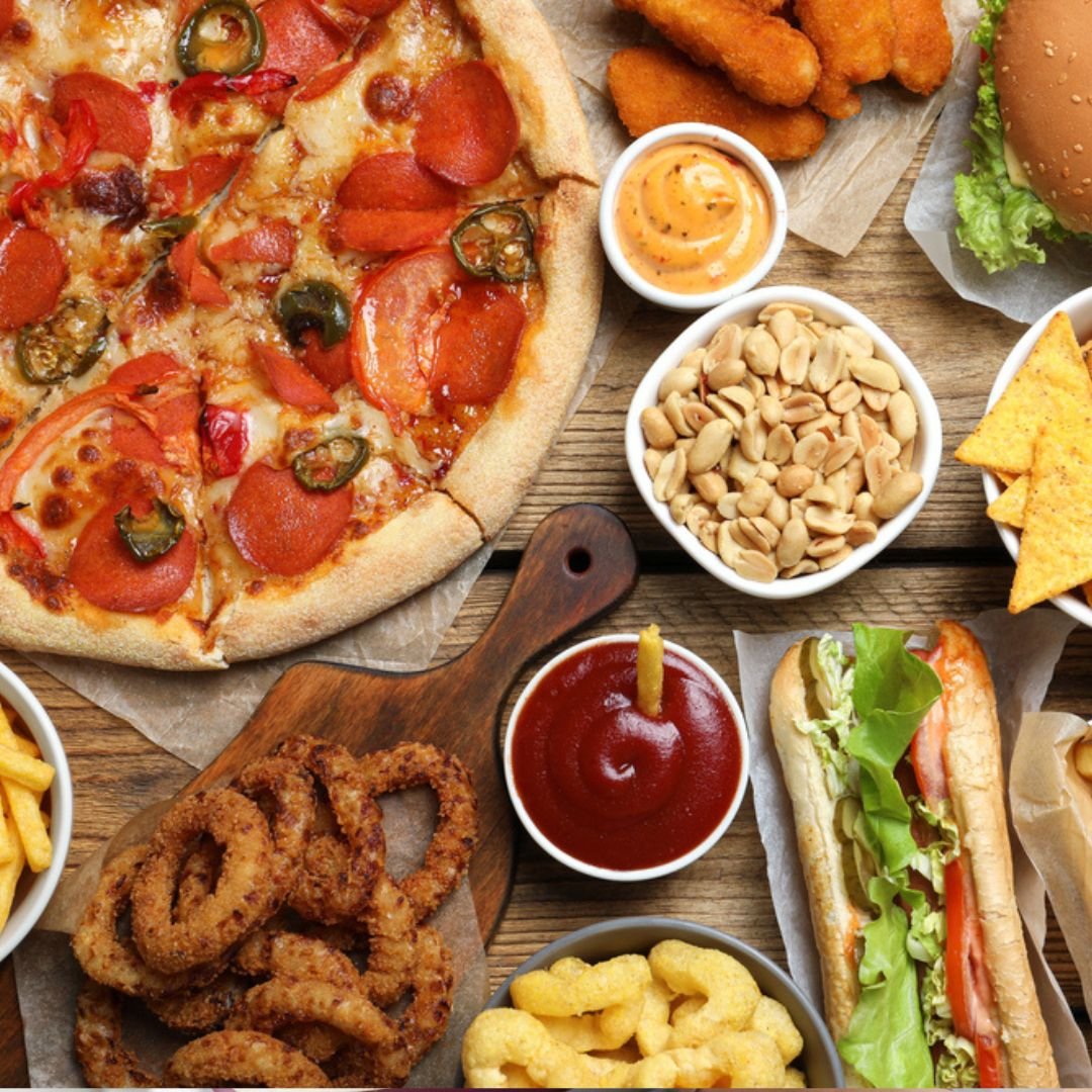 A tray of french fries, pizza, and dipping sauces representing common carbohydrate foods people often crave after restriction, illustrating the science behind dieting and cravings.