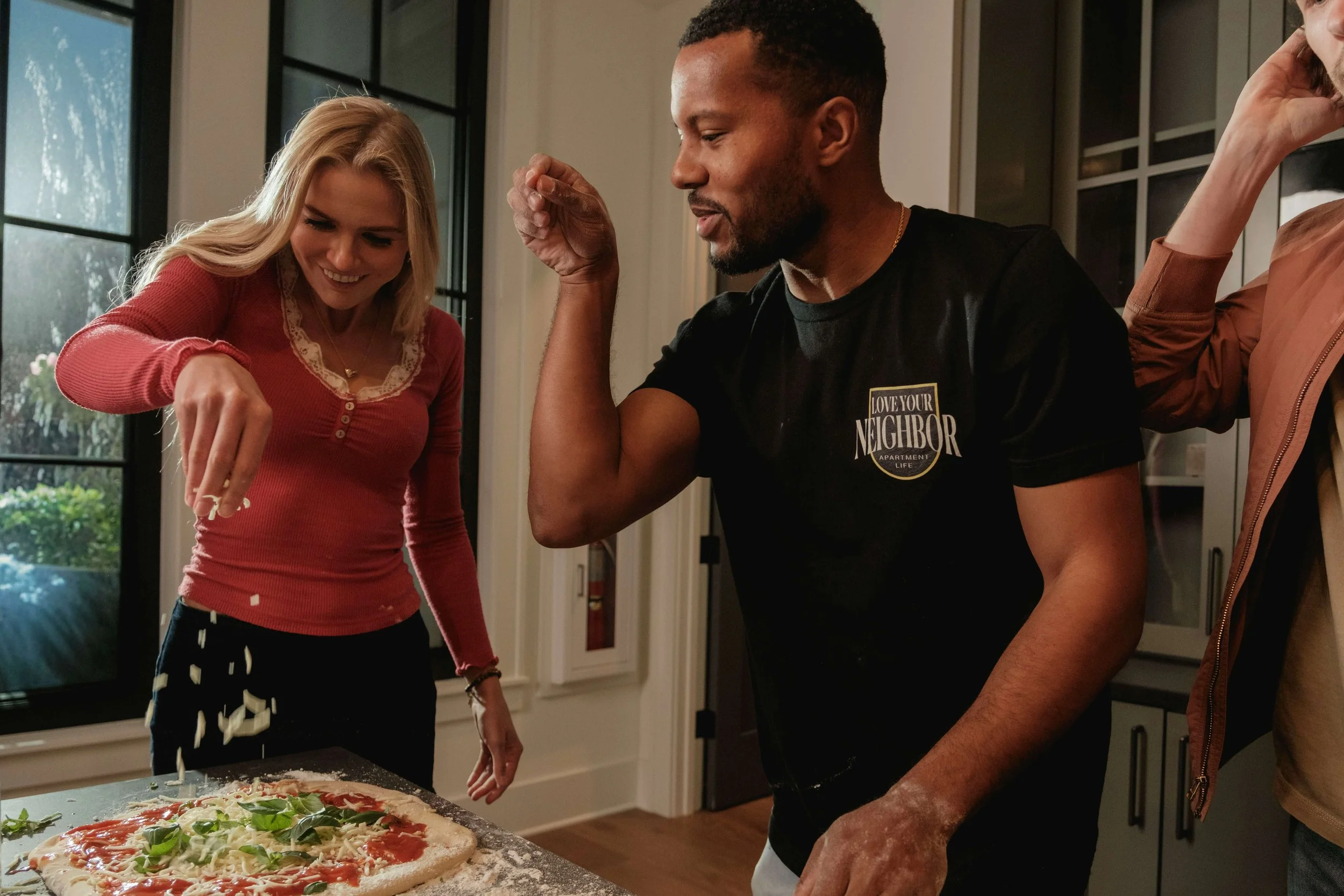 People preparing pizza together in a kitchen