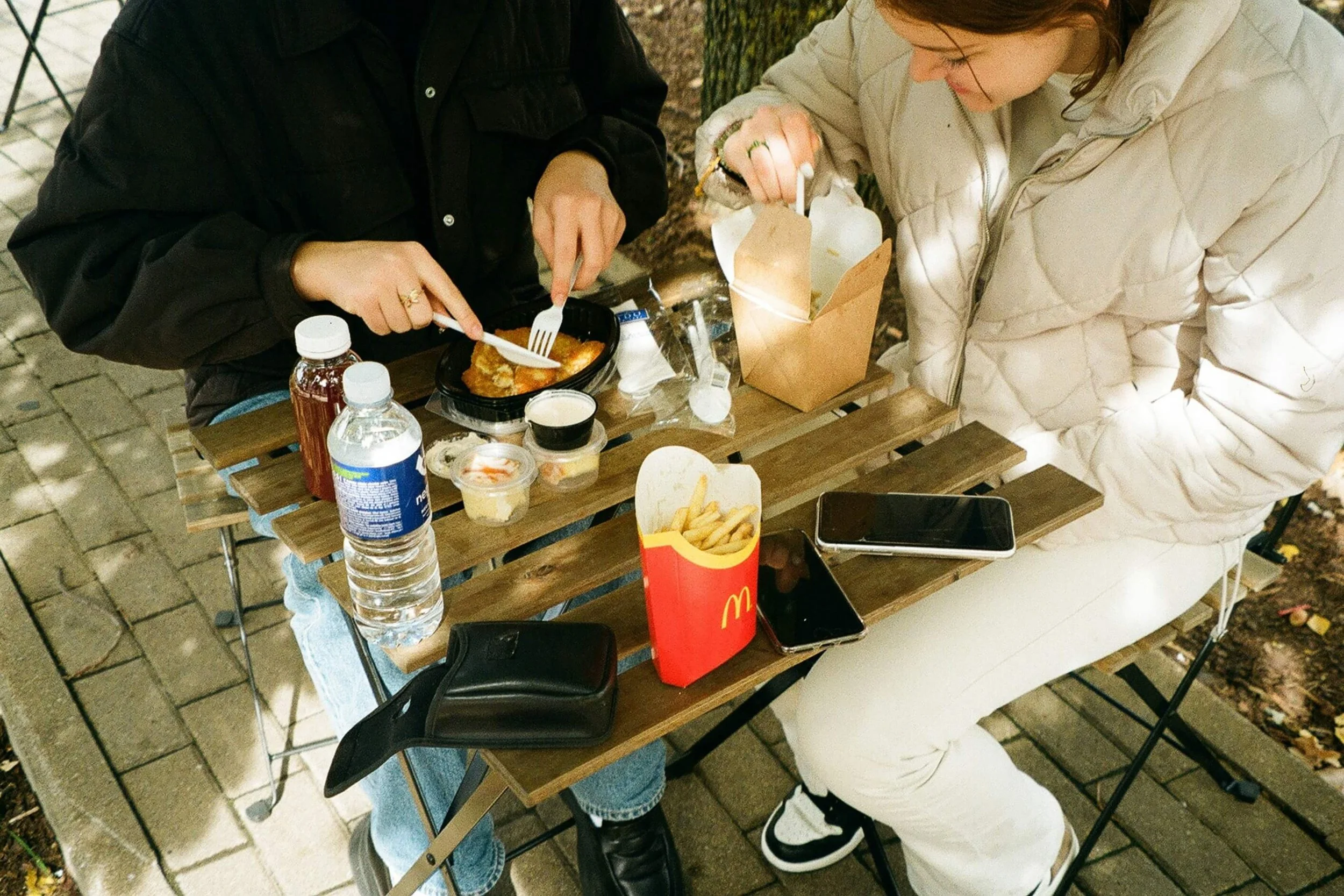 Two friends sharing a meal together at an outdoor café table.