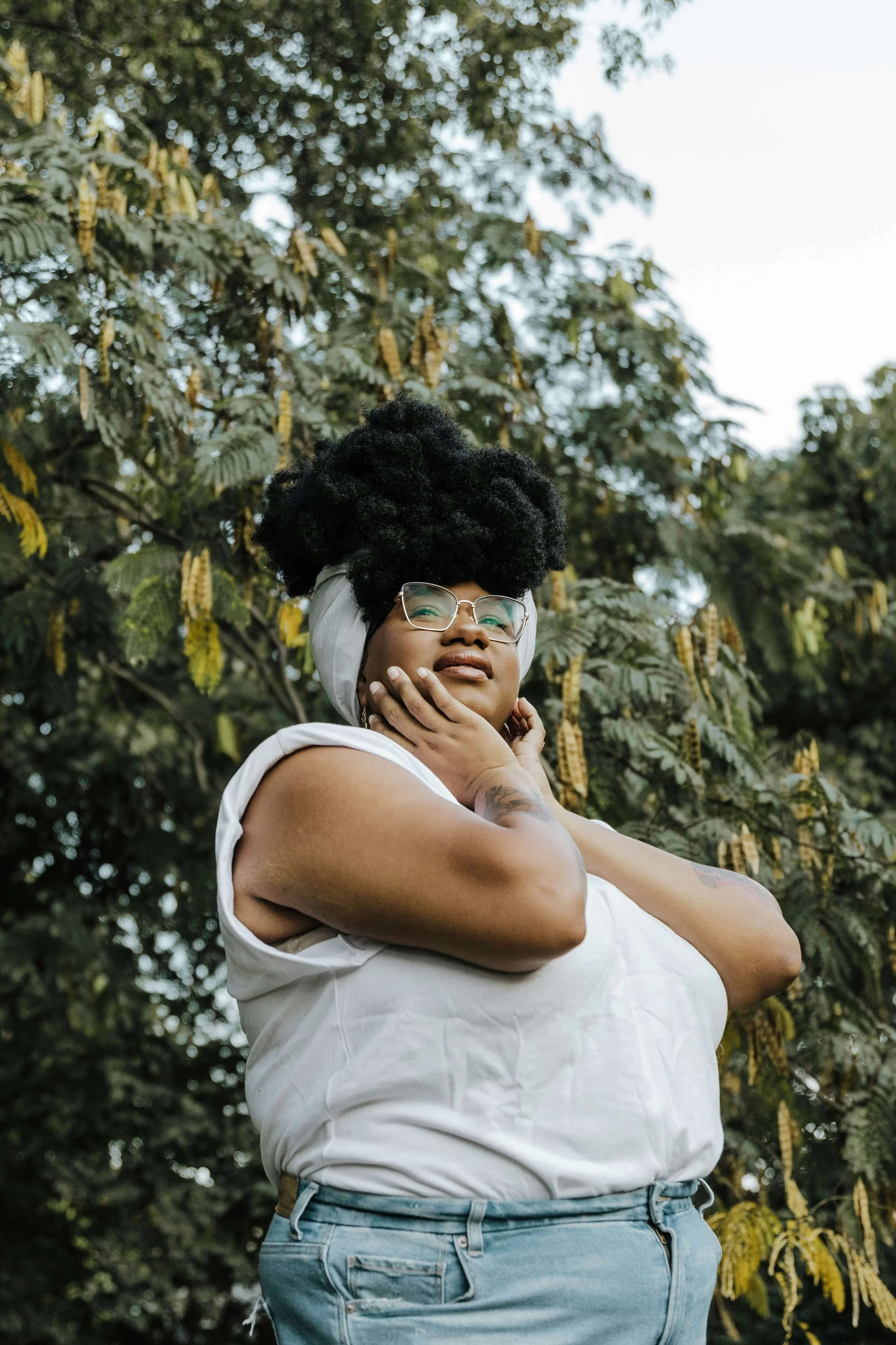 A black woman holds her face, gazing into the distance with contemplation