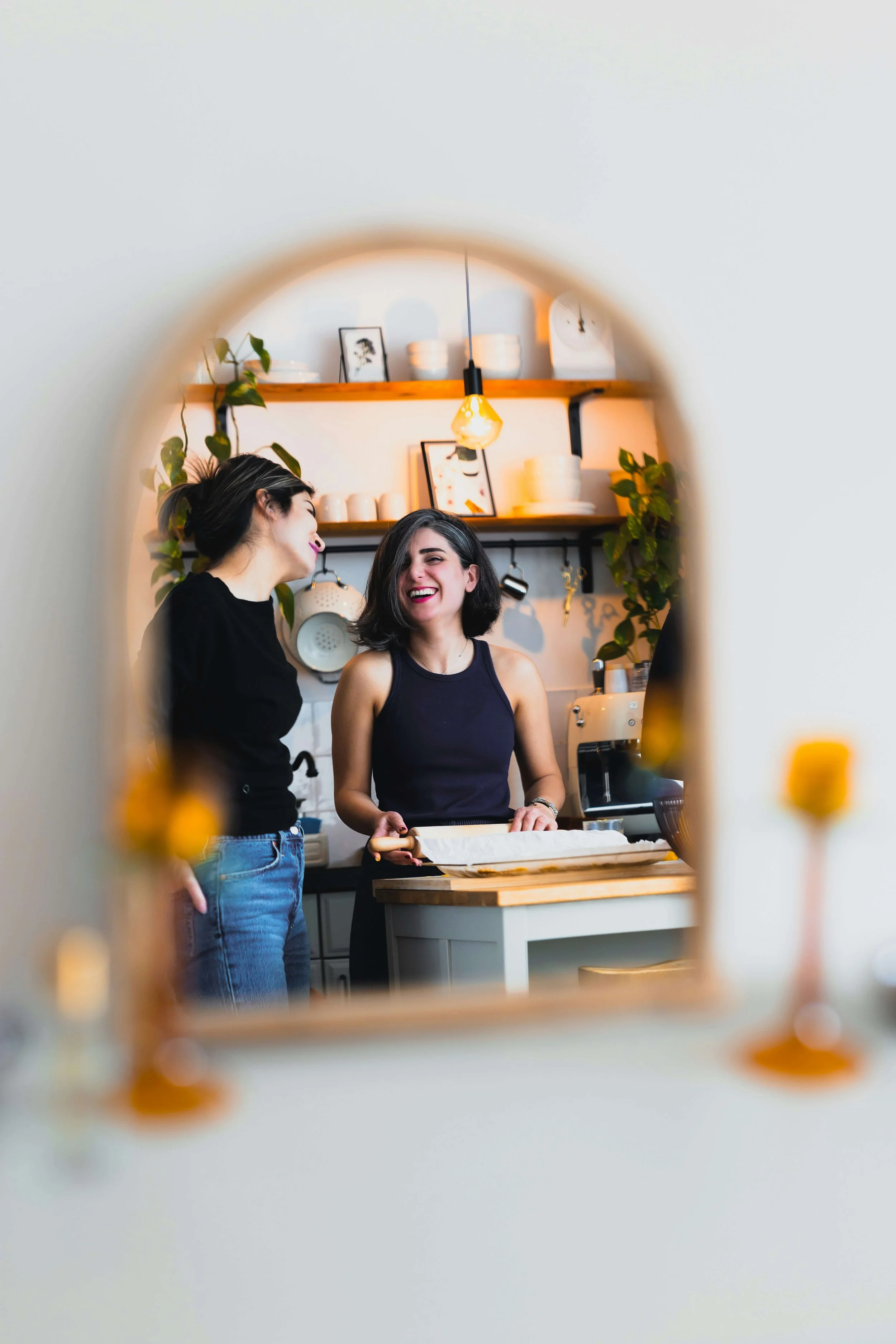 Two people smiling together while preparing food in a home kitchen.