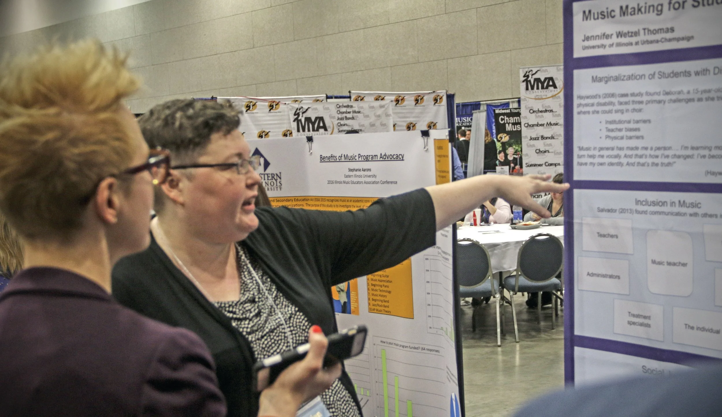 Two female professors discussing research at the i.m.e.c. poster session.