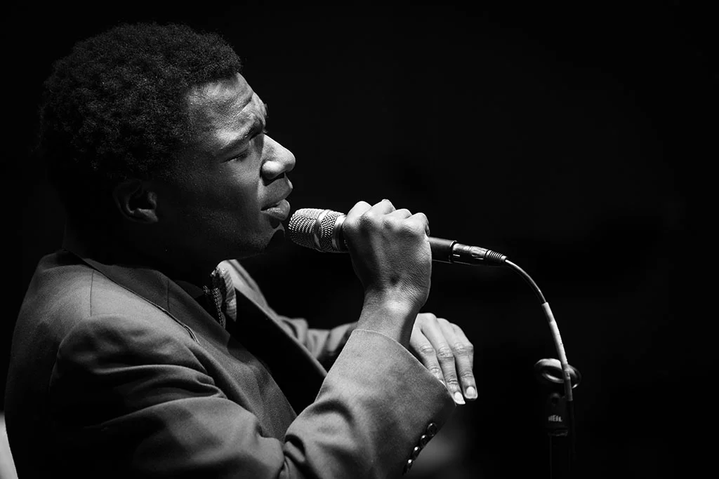 African American high school student singing with a microphone in an All-State vocal jazz performance.