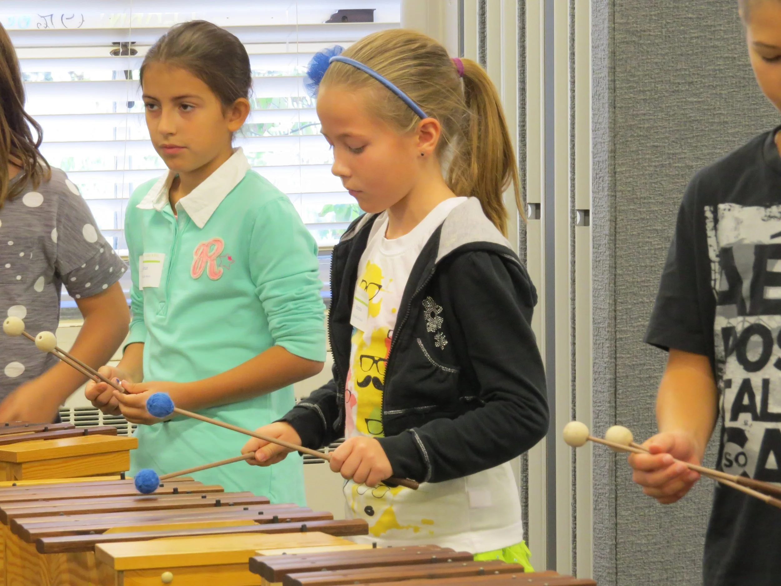 Students performing on wooden xylophones at an elementary festival.