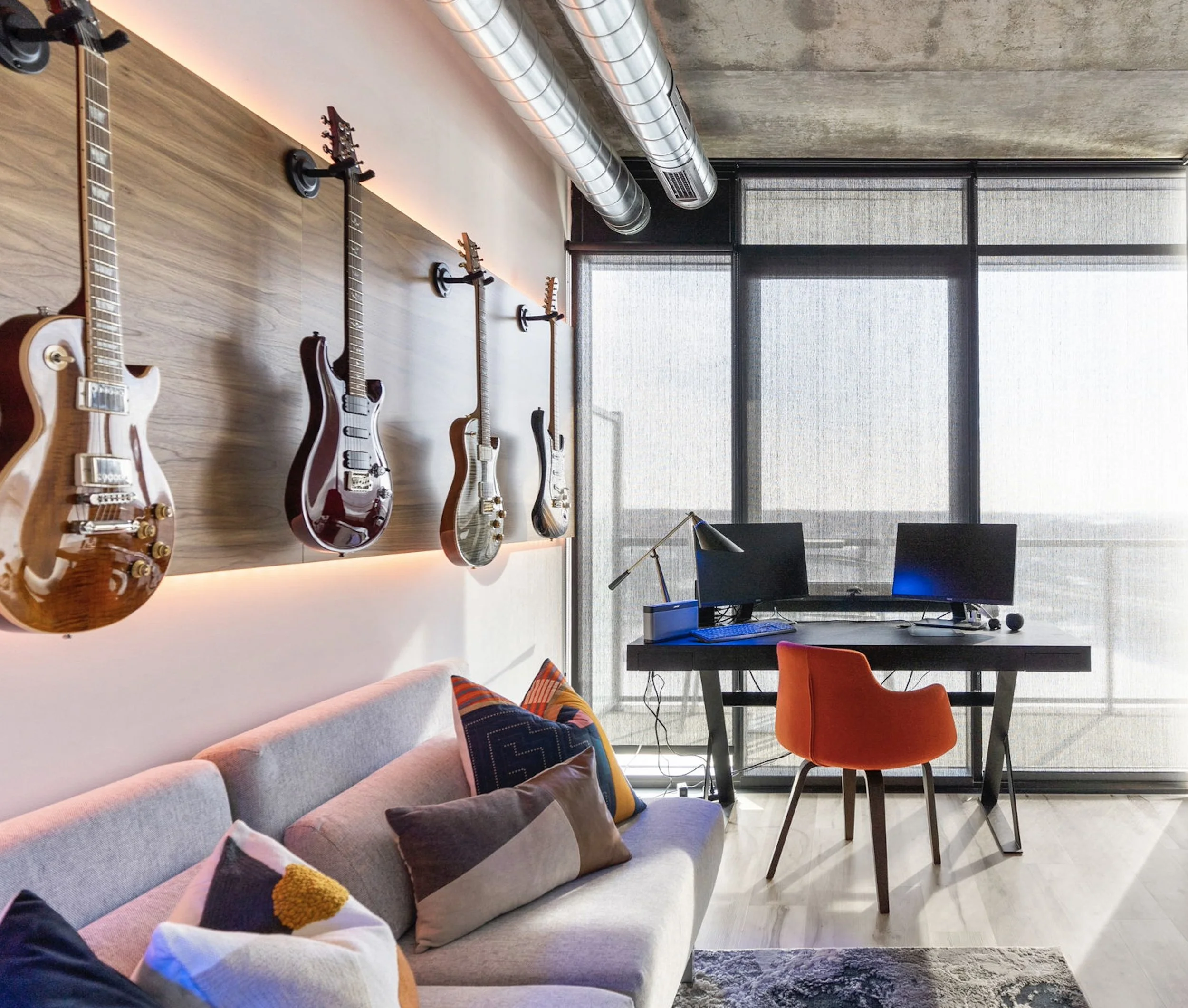 Home interior design in Saskatoon is shown in this is a custom loft home office design at River landing in Saskatoon. This custom loft home office at River Landing features an industrial vibe with a guitar wall and river views.