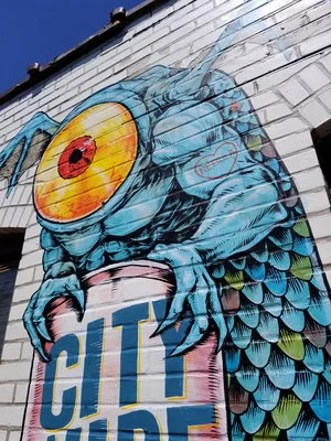 Killer Napkins. Graffiti of a blue one-eyed monster holds a can in it’s claws.