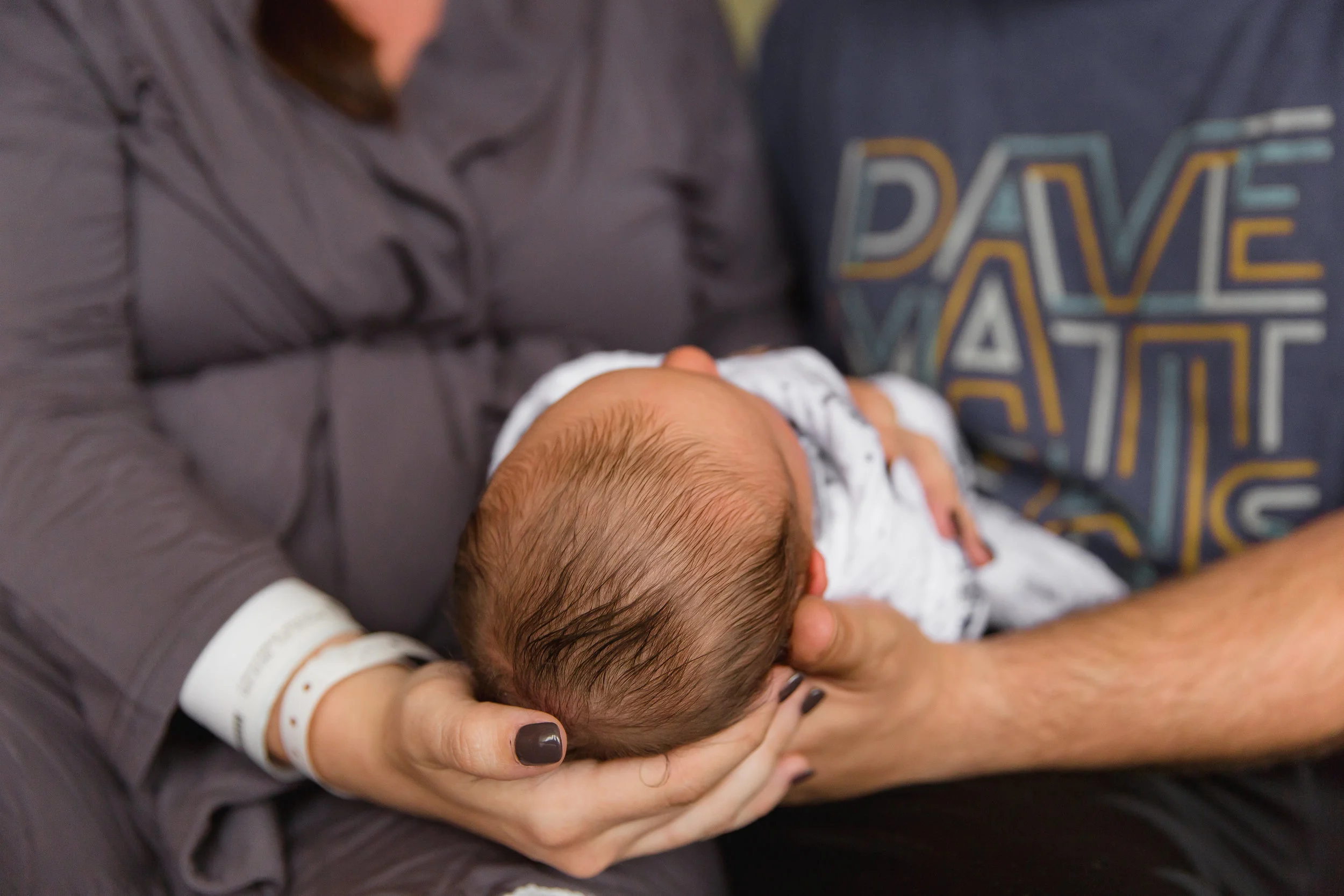 top of newborn baby boy head, mom and dad holding baby