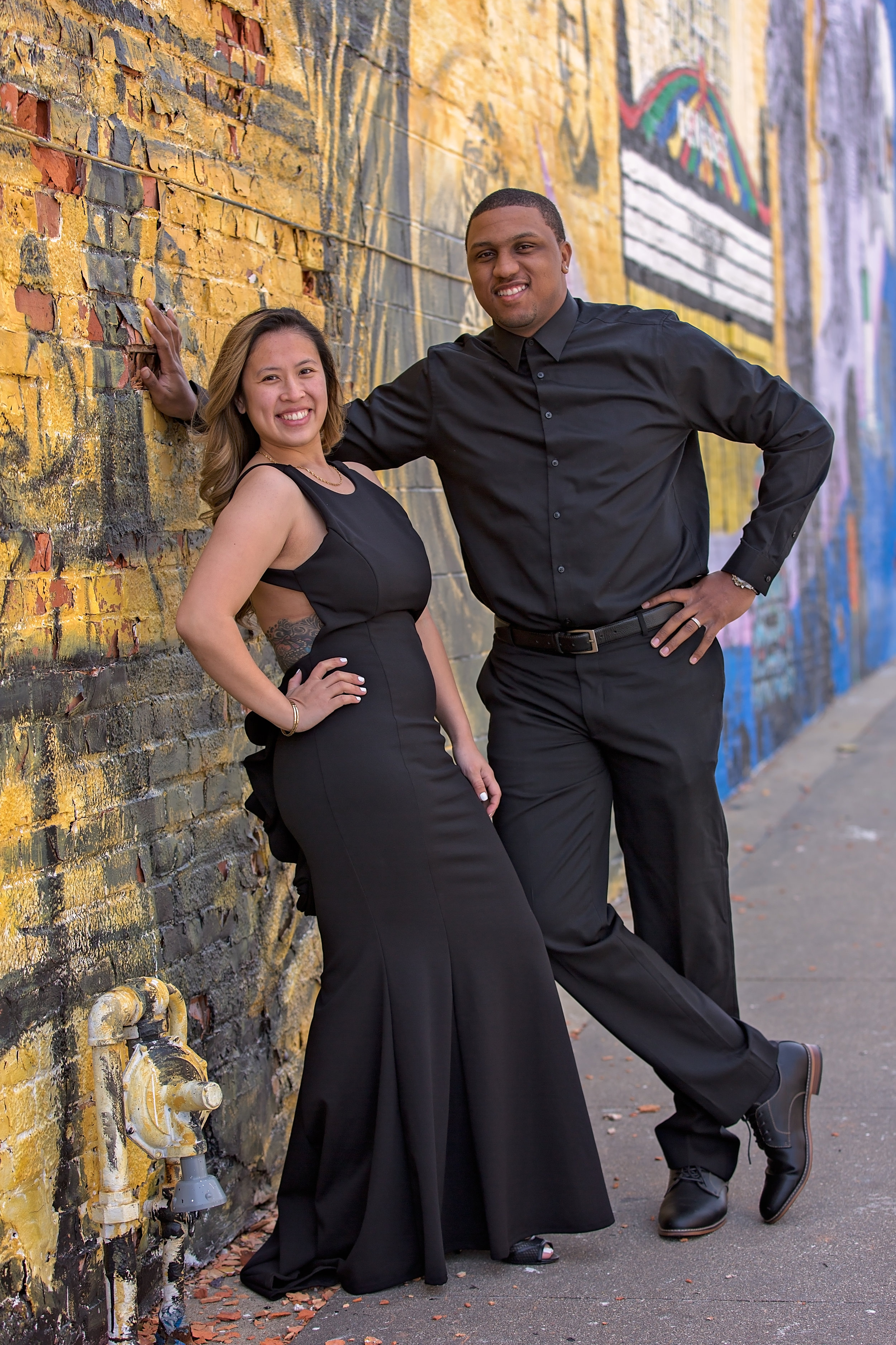 husband and wife posing by city wall couples session
