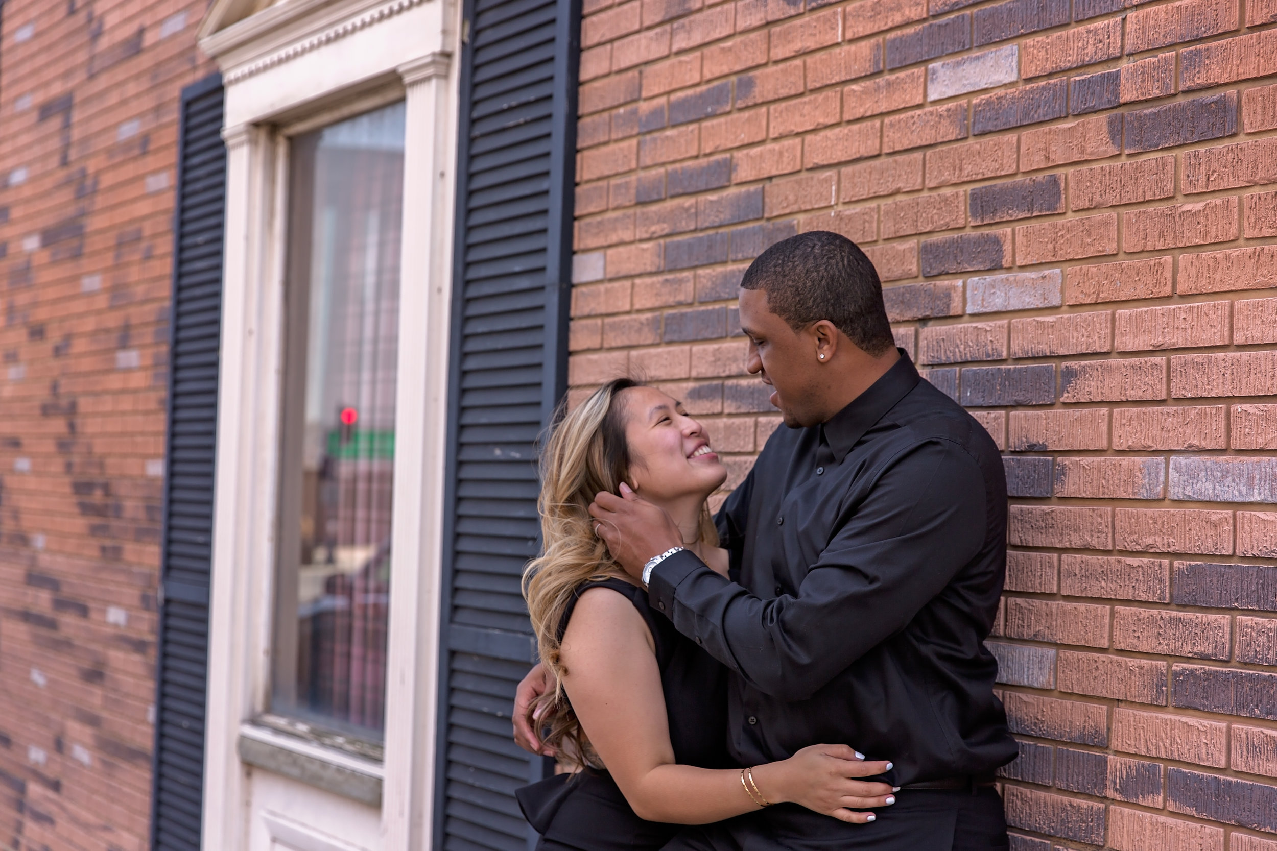 couple leaning up against brick wall embracing