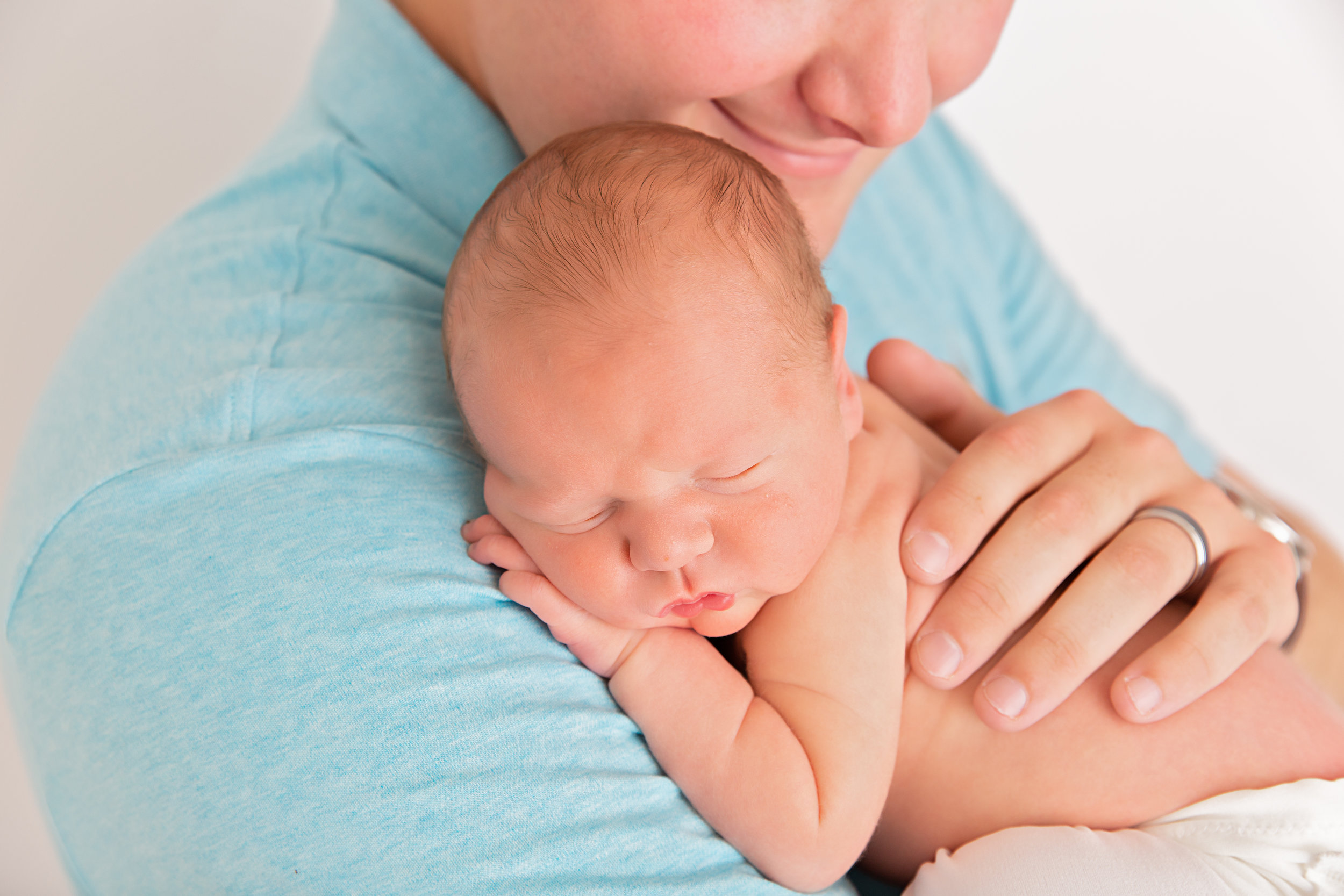 newborn baby sleeping snuggled on daddy